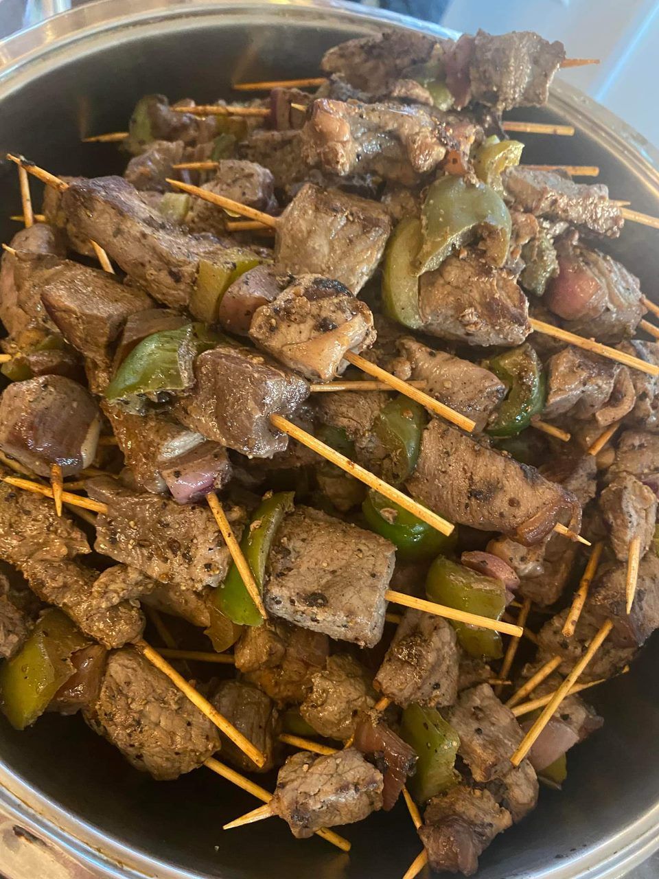 A bowl filled with meat and vegetables on skewers.