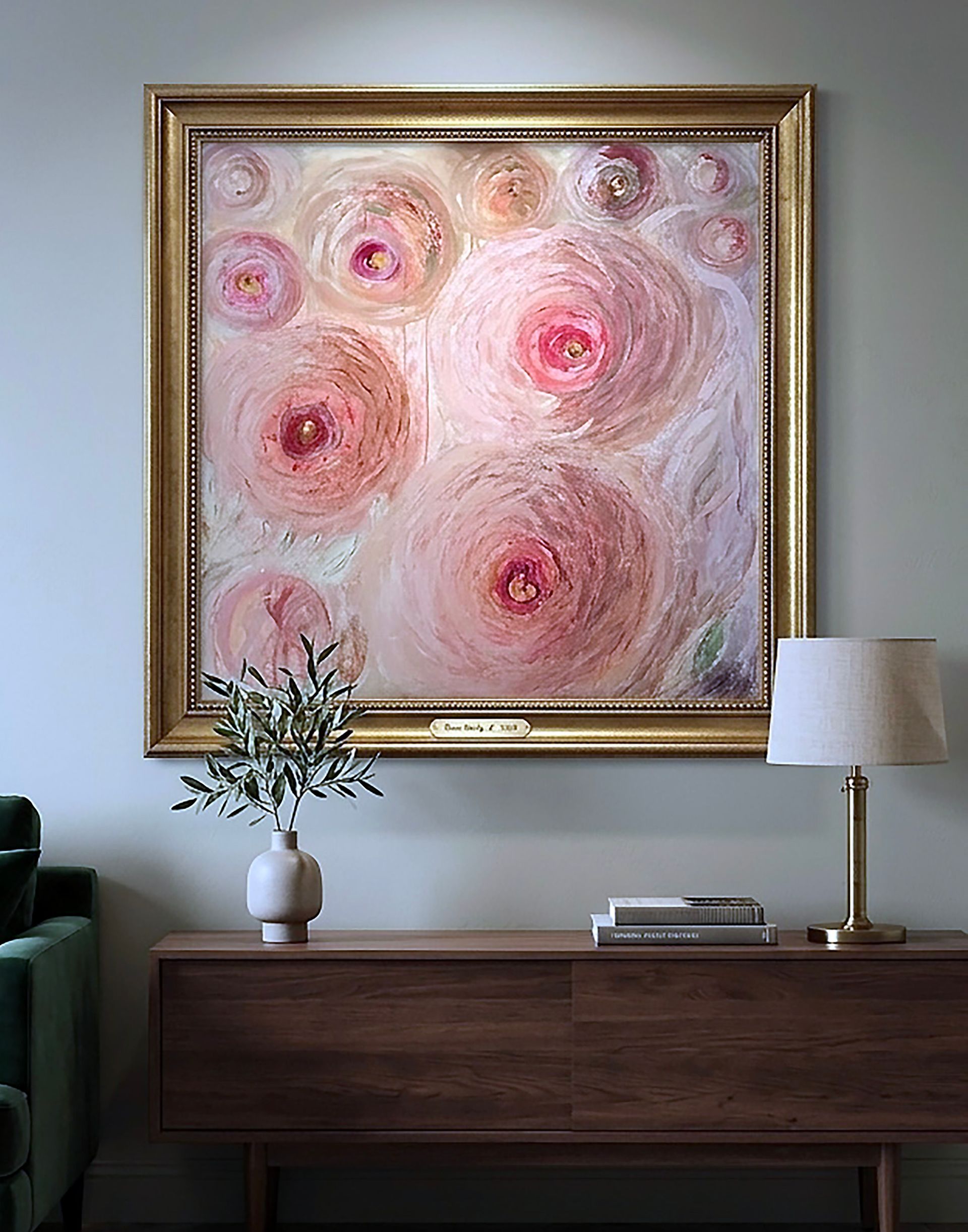 Een abstract schilderij met roze bloemen boven een houten consoletafel met lamp en vaas in een moderne woonkamer.