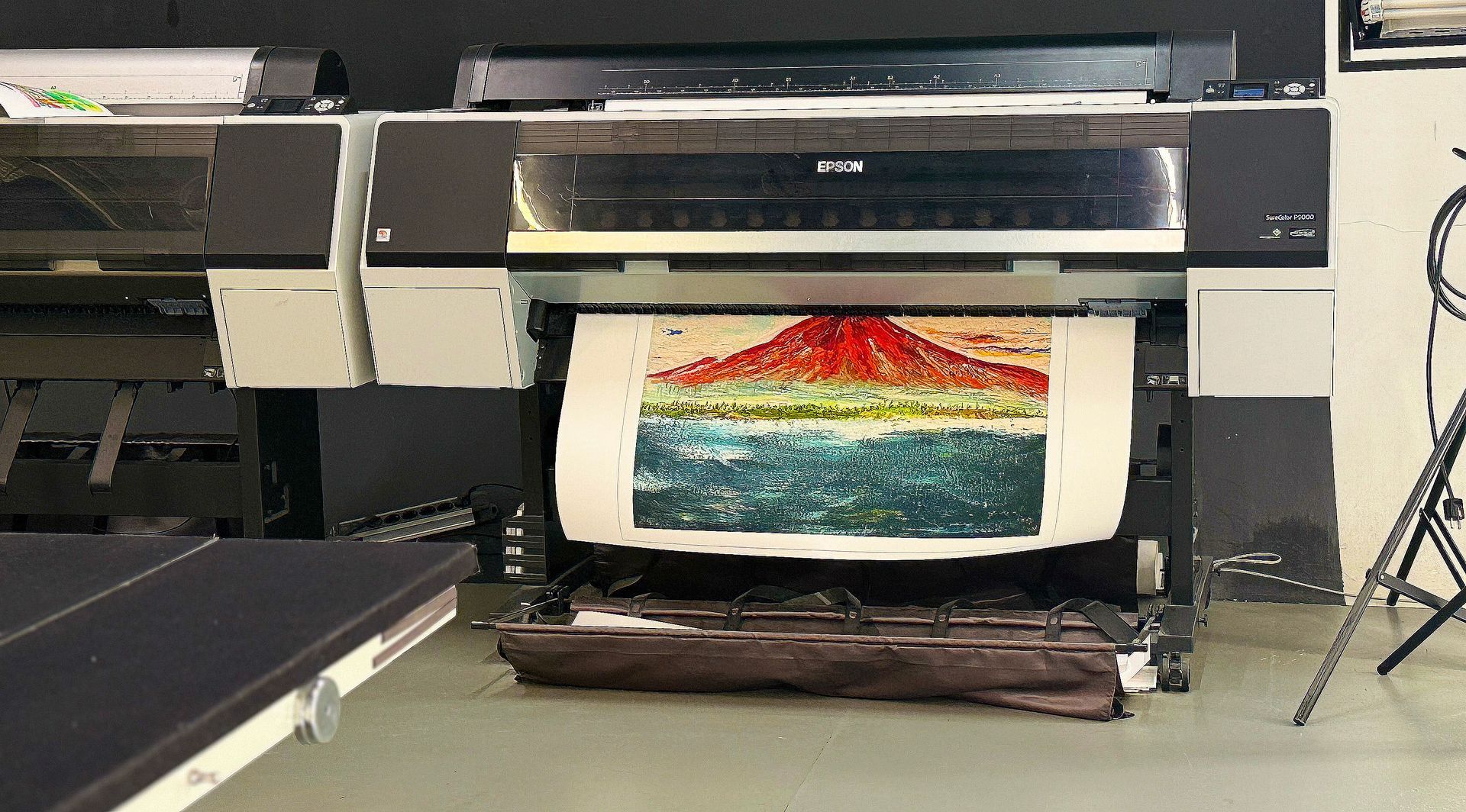 Een grootformaatprinter print een kleurrijke landschapsafbeelding in een werkplaats.