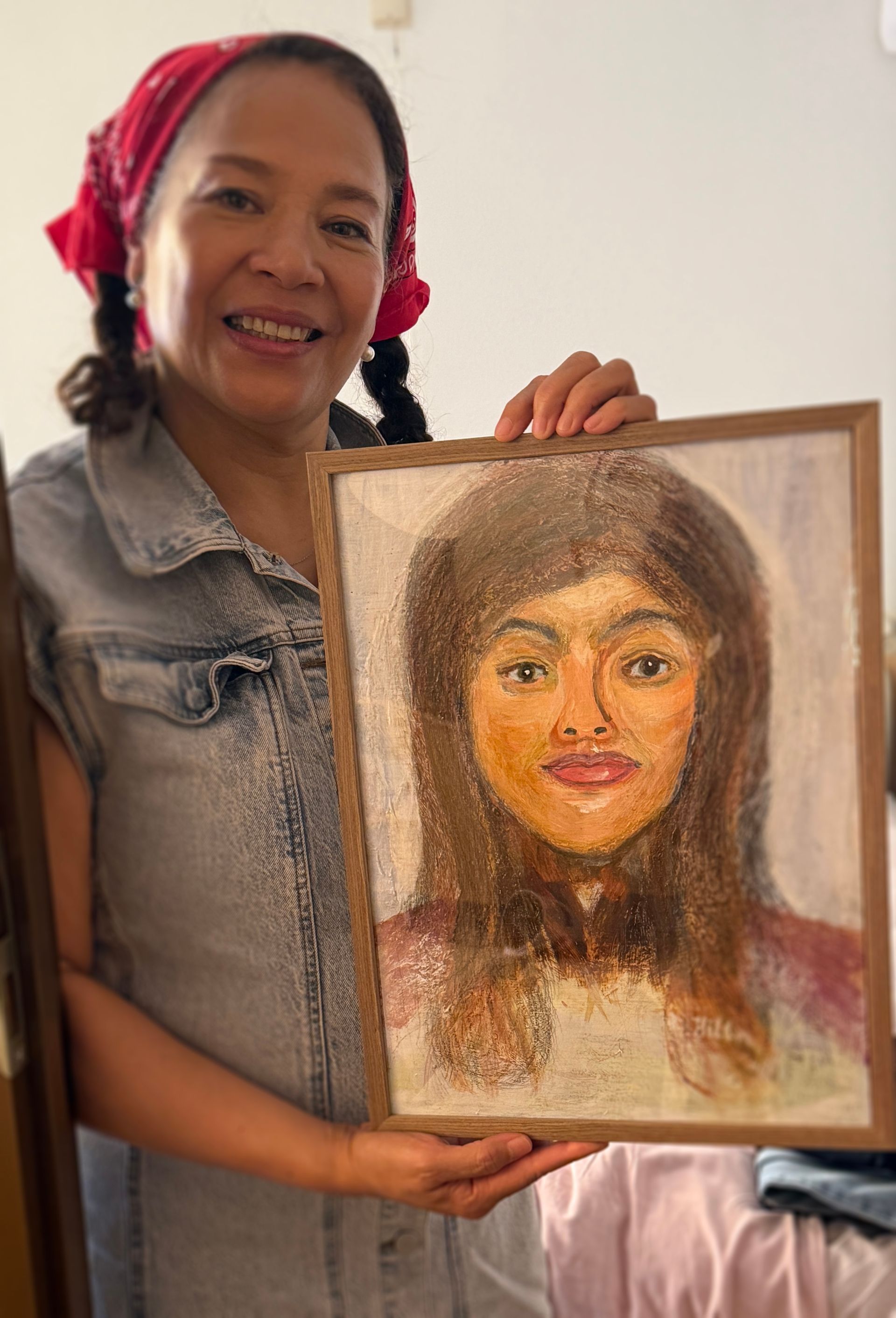 Vrouw met een ingelijst portret van een lachend persoon met gevlochten rood haar.