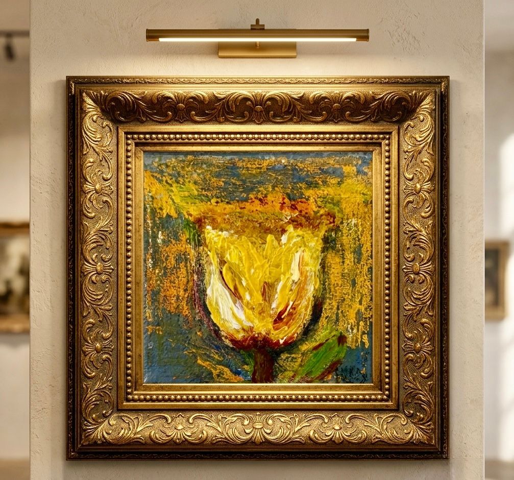 Titel: Tussen Stilte En Bloei
Ingelijst abstract schilderij van een gele tulp aan een beige muur, verlicht door een messing schilderijlamp.