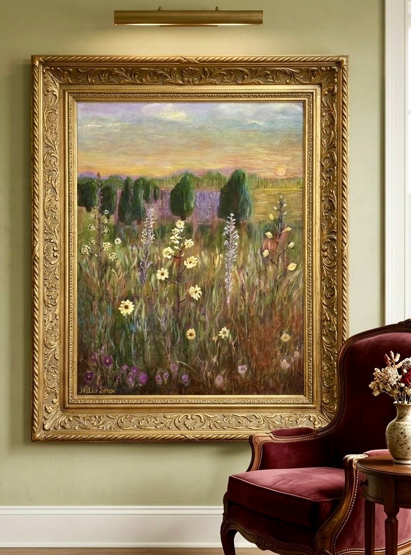 Ingelijst schilderij van een bloemenlandschap boven een rode fluwelen stoel in een zacht verlichte kamer.