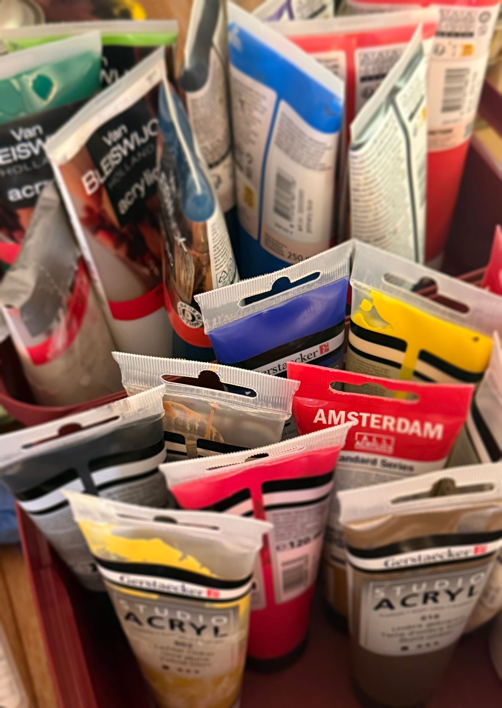 Diverse tubes acrylverf in een bakje, met kleurrijke dopjes en zichtbare etiketten.