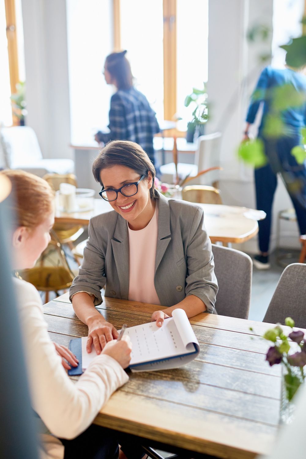 Two people discussing over documents at a table in a bright office lounge