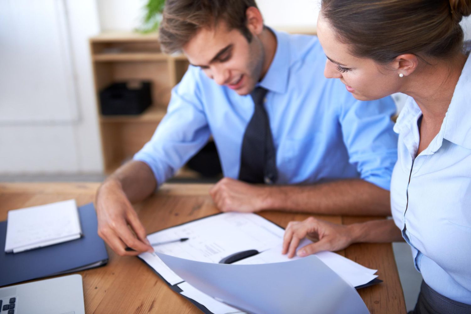 Two coworkers reviewing documents at a desk in a bright office