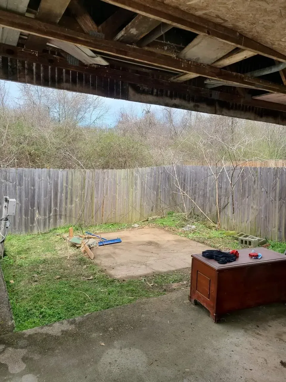 A ladder is sitting in the grass next to a brick wall.