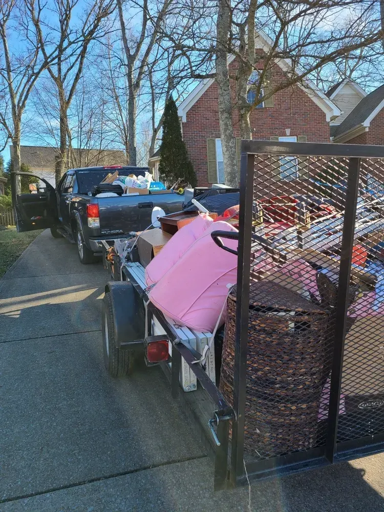 A truck is pulling a trailer full of junk.