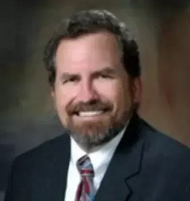 A man in a suit and tie is smiling for the camera.