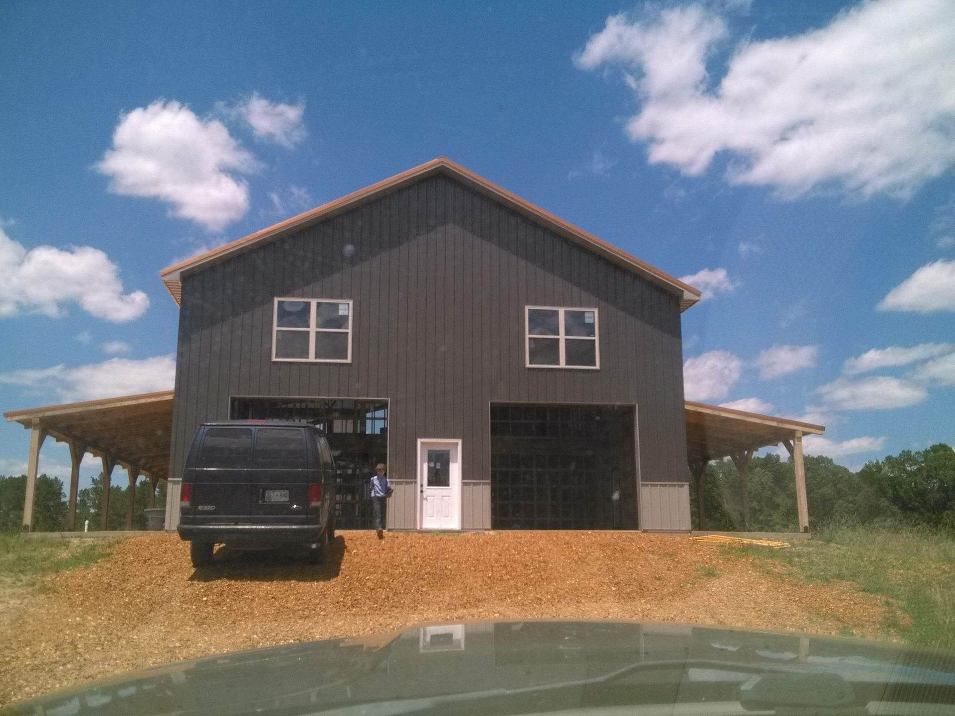 A black van is parked in front of a large barn