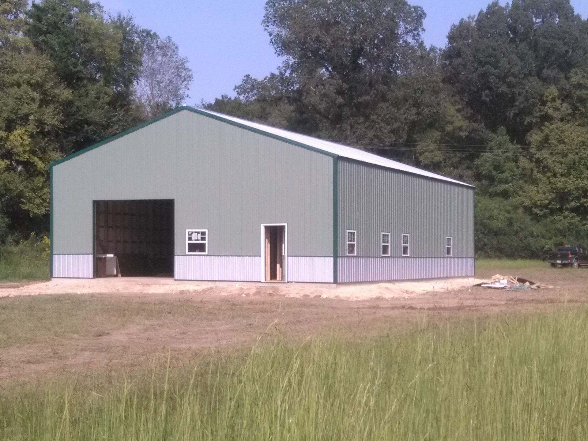 A green and white building in a field with trees in the background