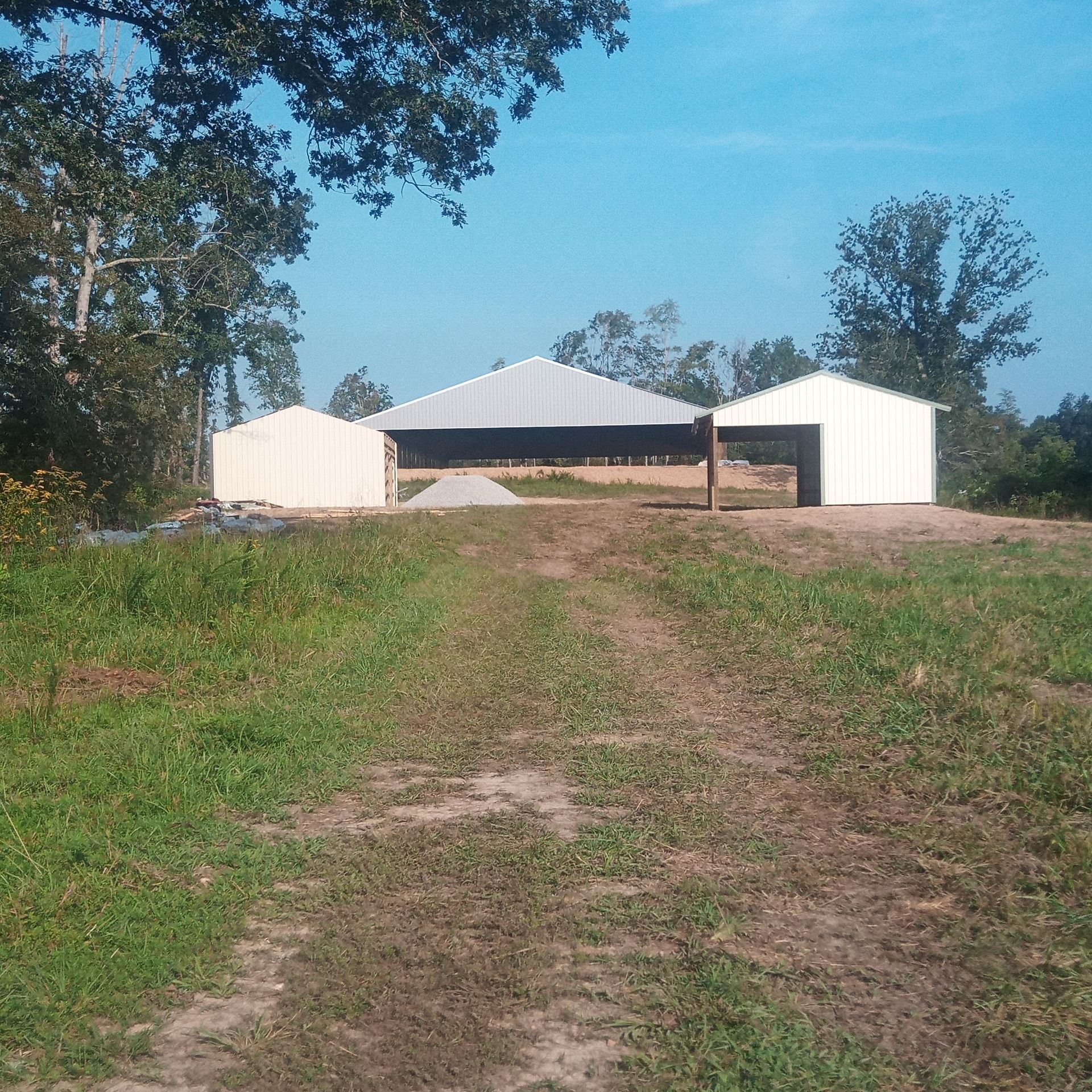 A white barn is sitting in the middle of a grassy field