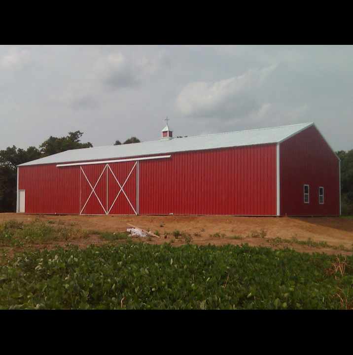 A large red barn is sitting in the middle of a field