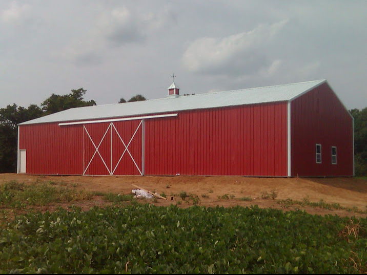 A large red barn with a white roof is in a field