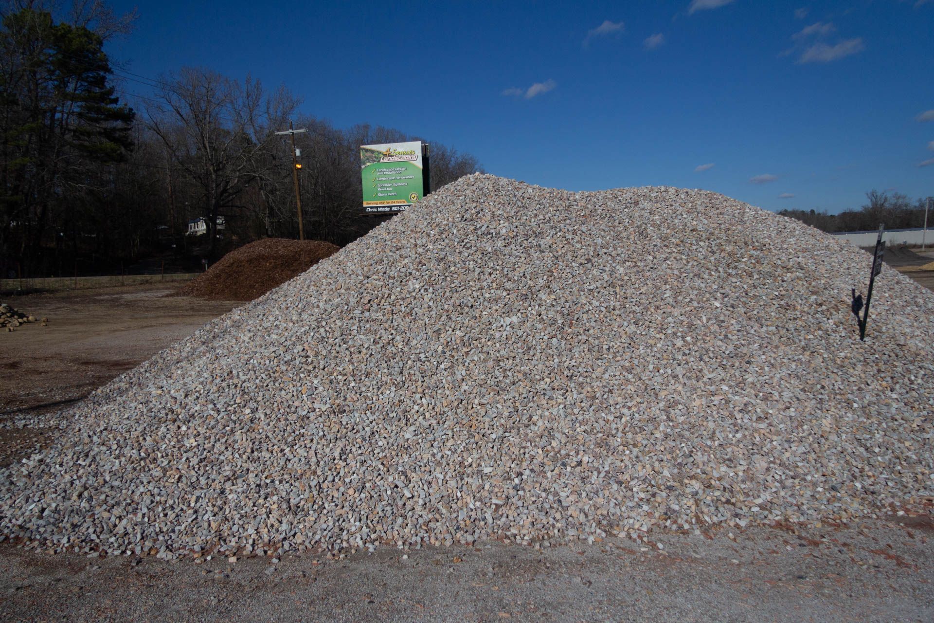 A large pile of gravel is sitting in the middle of a dirt field.