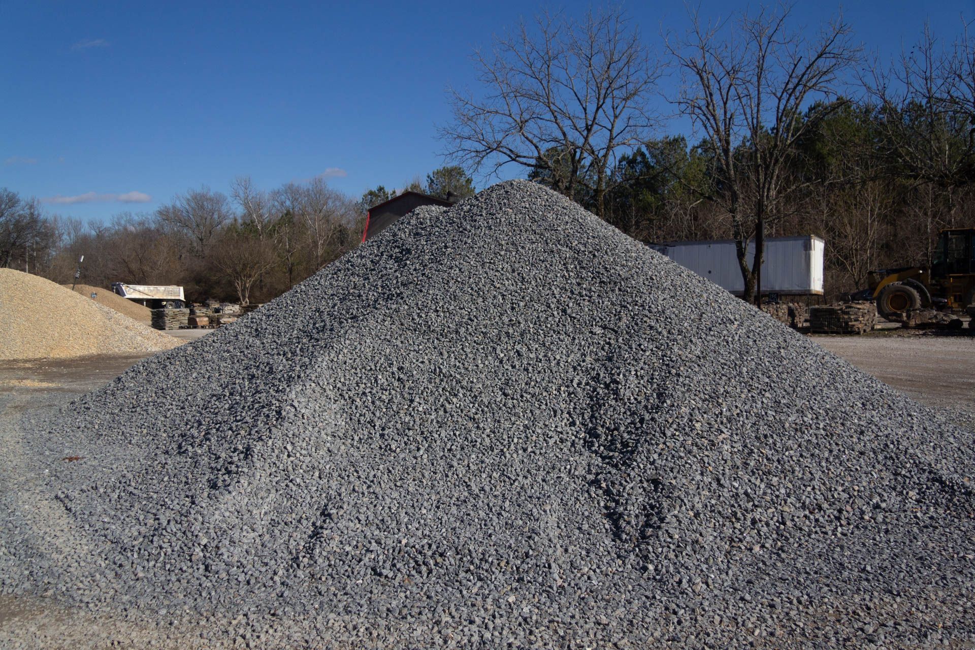 A pile of gravel is sitting in the middle of a dirt field.