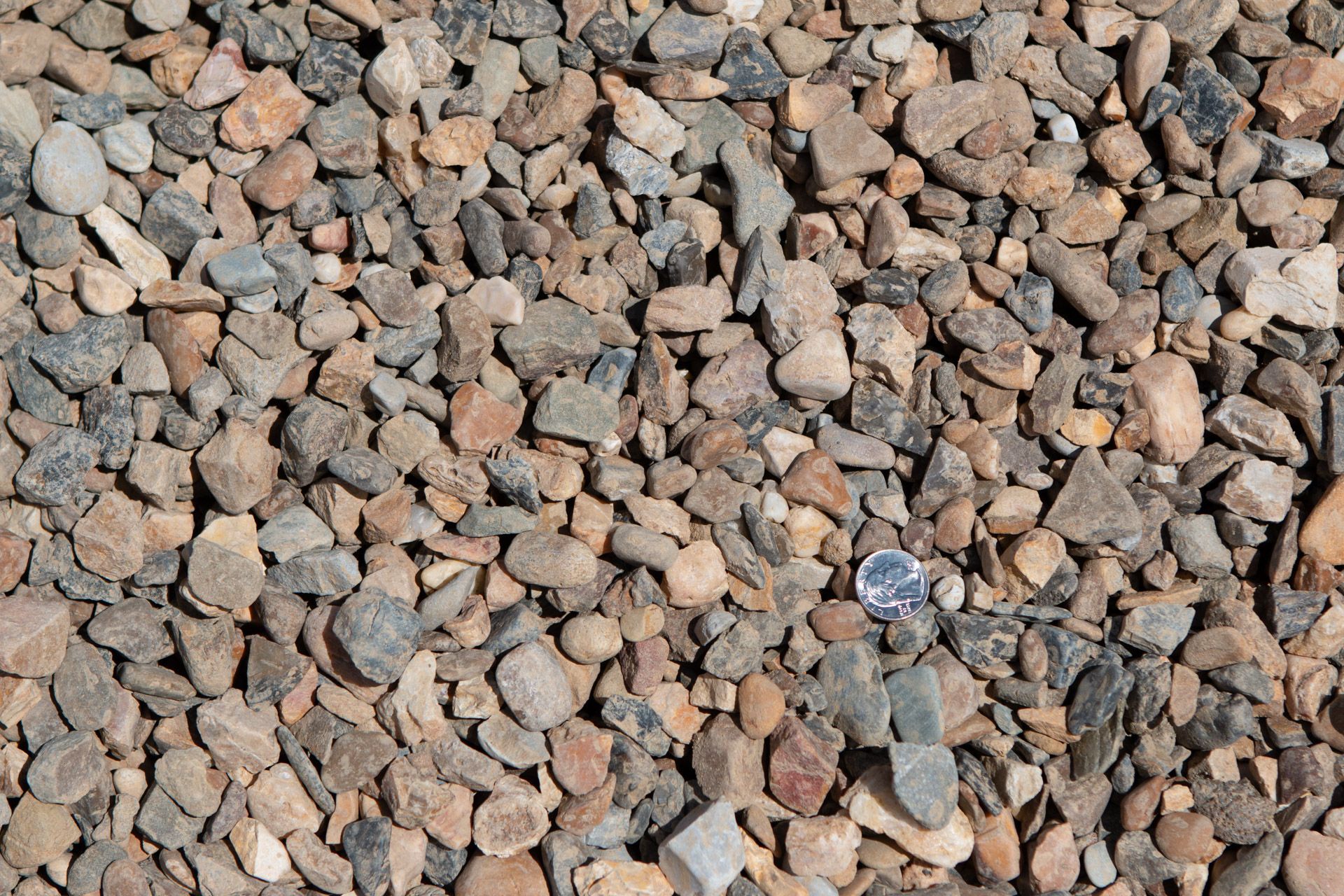 A pile of rocks with a quarter in the middle.