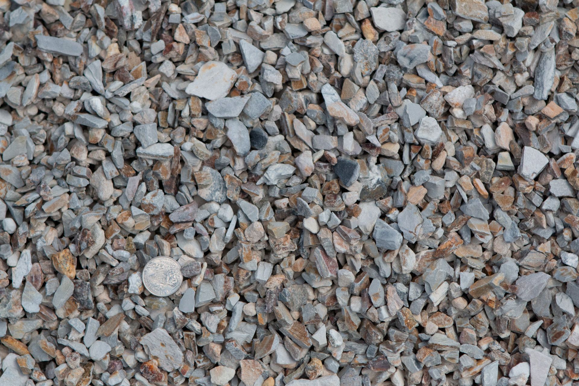 A pile of gravel with a quarter in the middle.