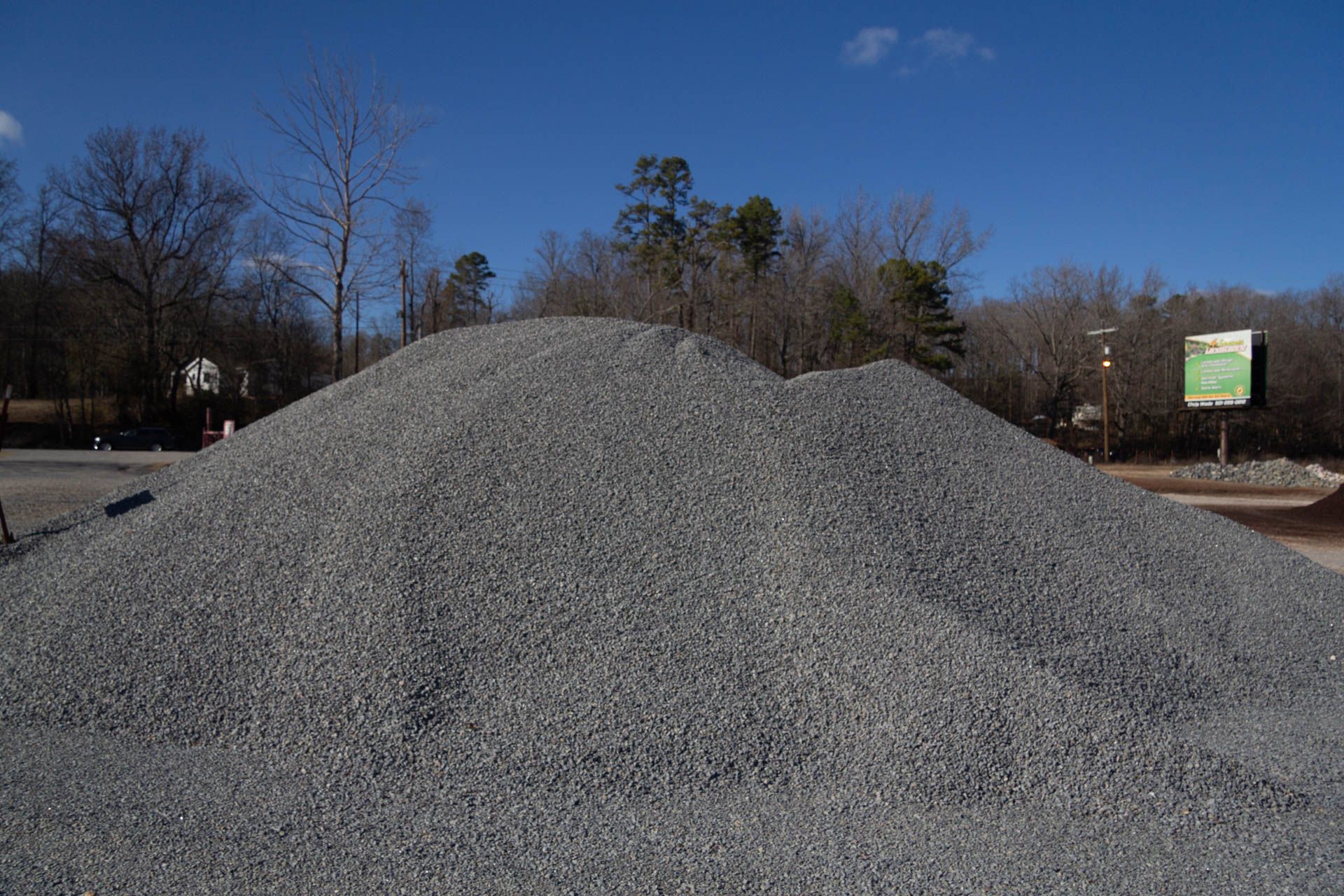 A large pile of gravel is sitting on the side of the road.