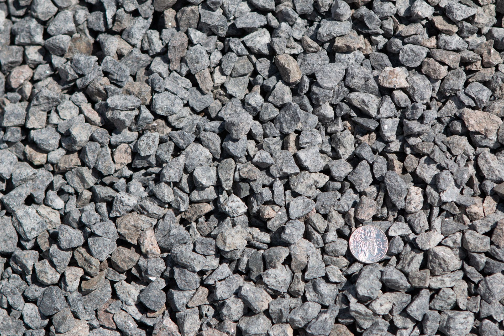 A pile of gravel with a quarter in the middle.