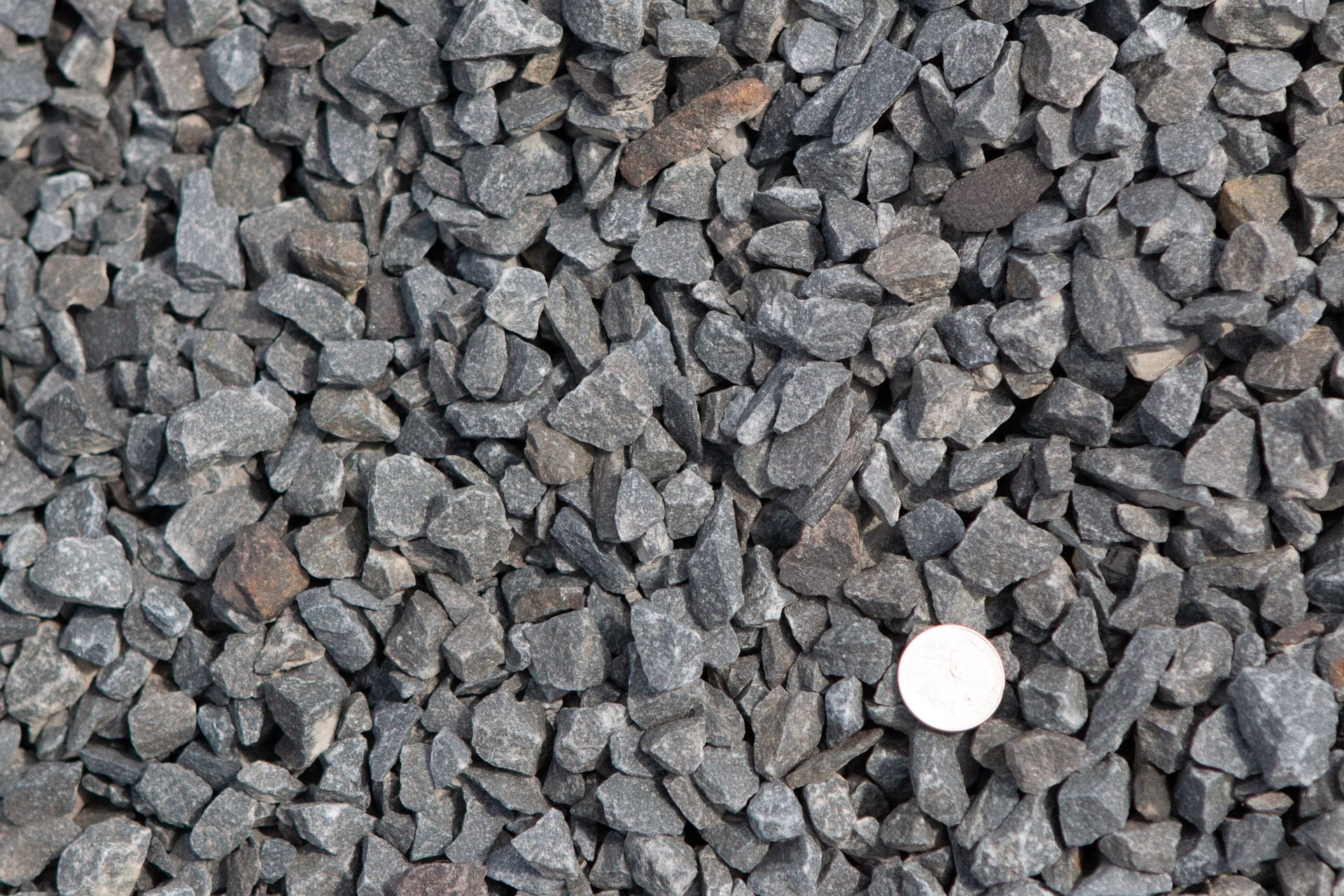 A pile of gravel with a coin in the middle.