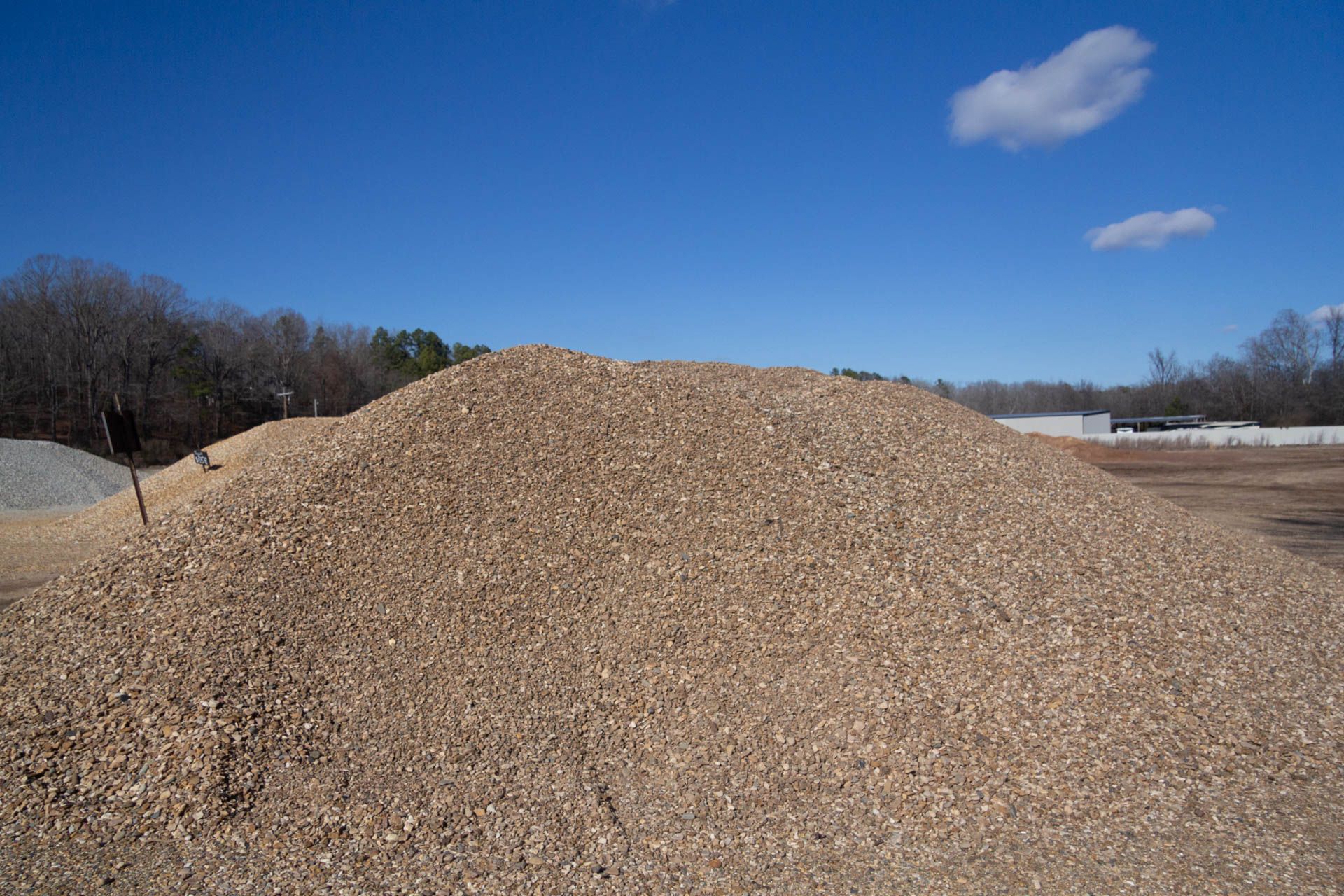 A large pile of gravel is sitting in the middle of a dirt field