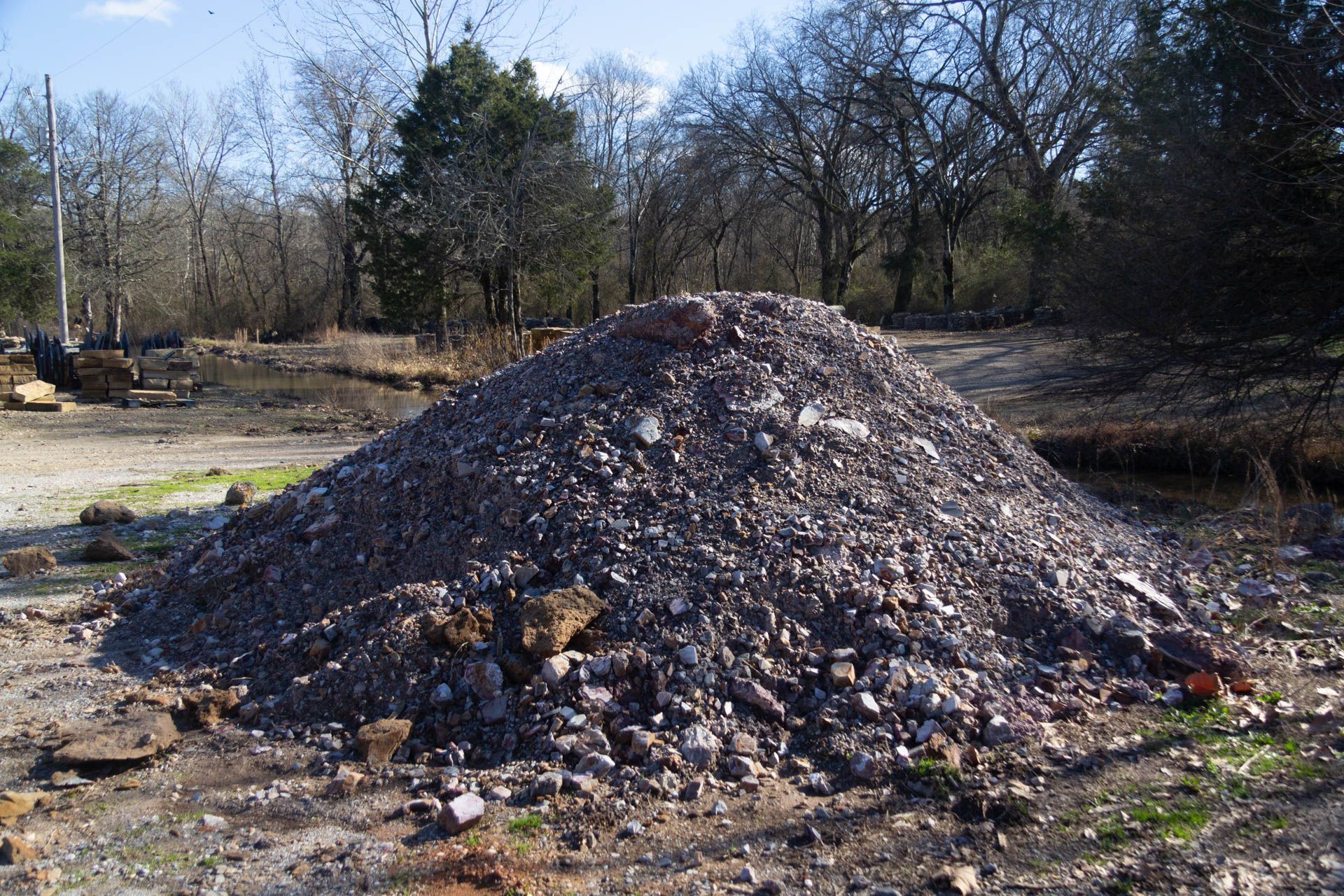 A pile of rocks in a field with trees in the background