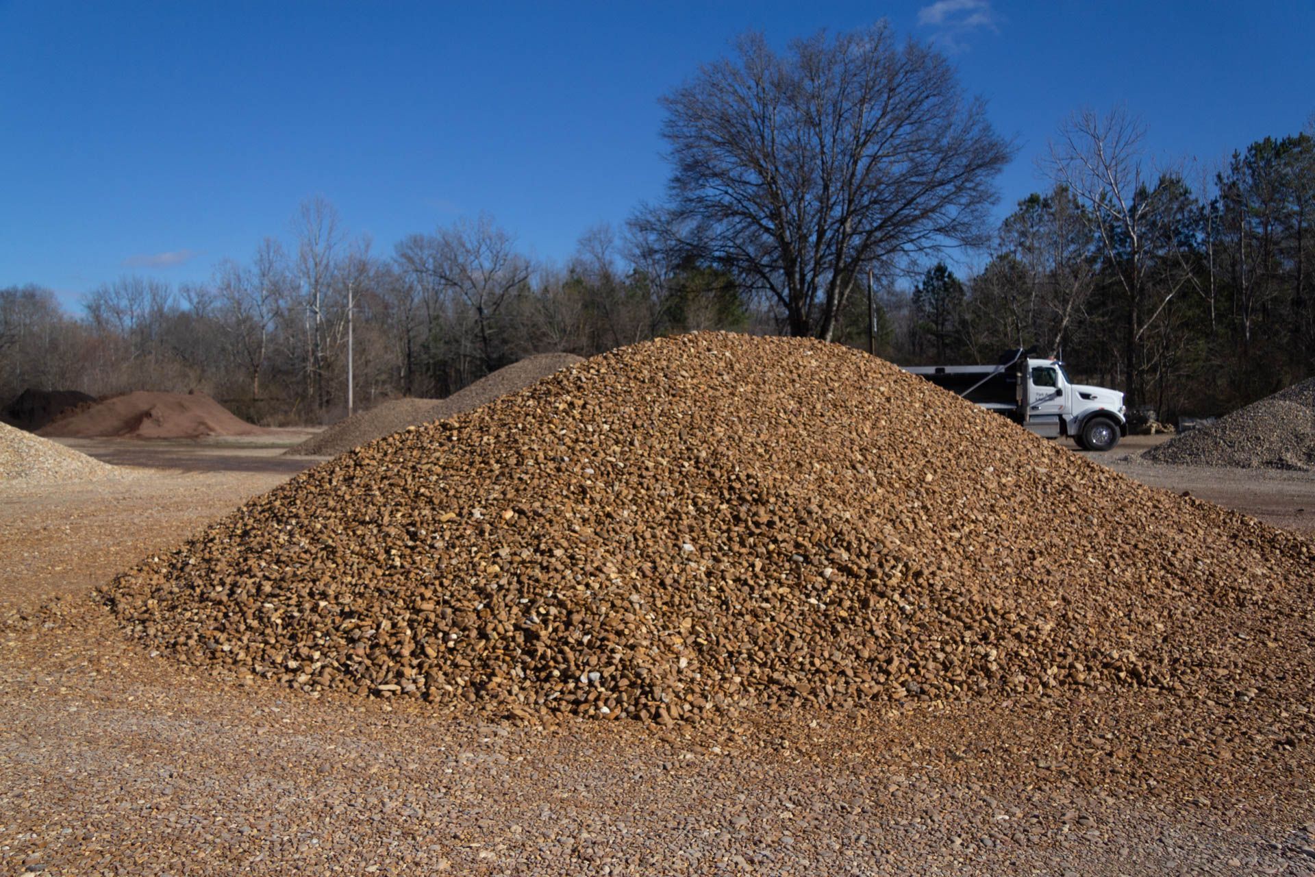 A truck is parked in front of a pile of wood chips