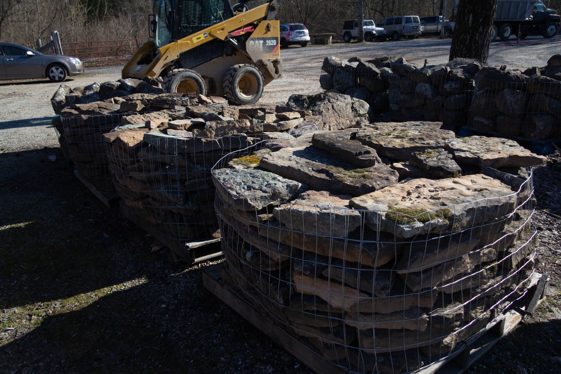 A bulldozer is moving a pile of rocks in a parking lot