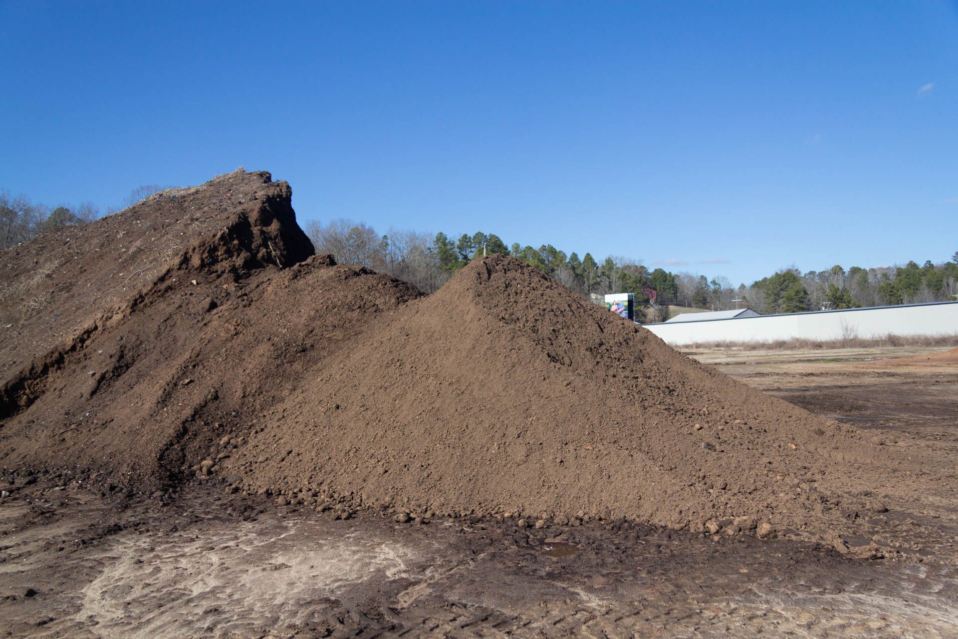 There is a large pile of dirt in the middle of a field.