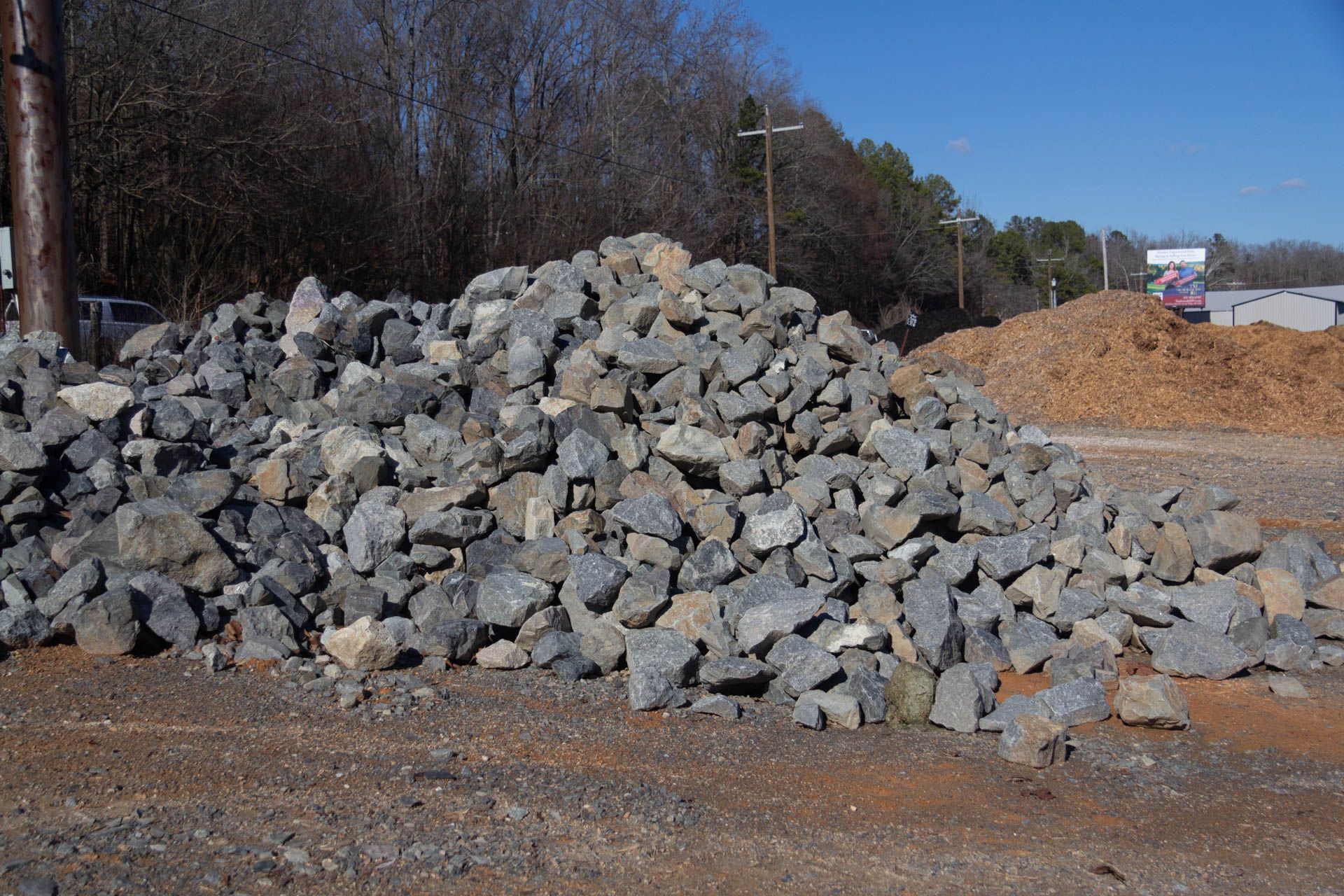 A pile of rocks in a dirt field with trees in the background