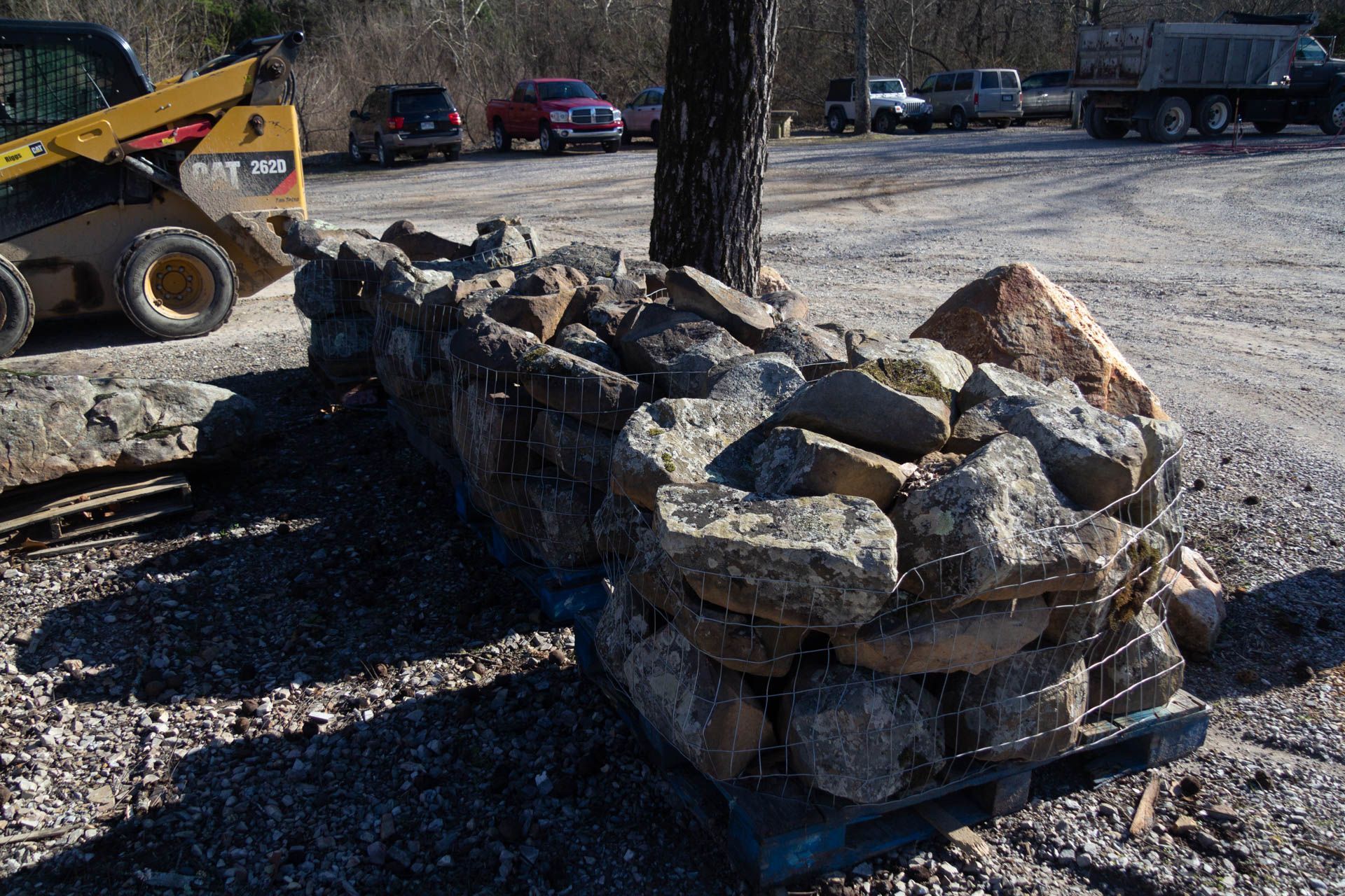 A pile of rocks is sitting next to a bulldozer in a parking lot