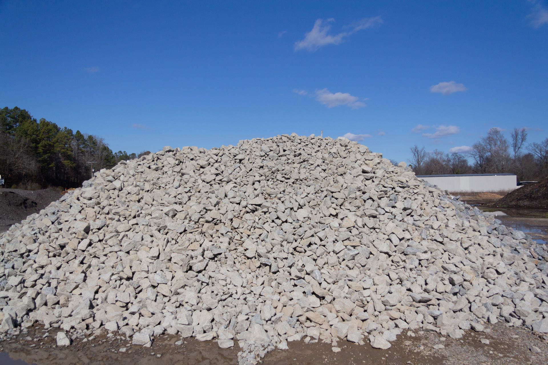 A large pile of gravel is sitting on top of a dirt field.