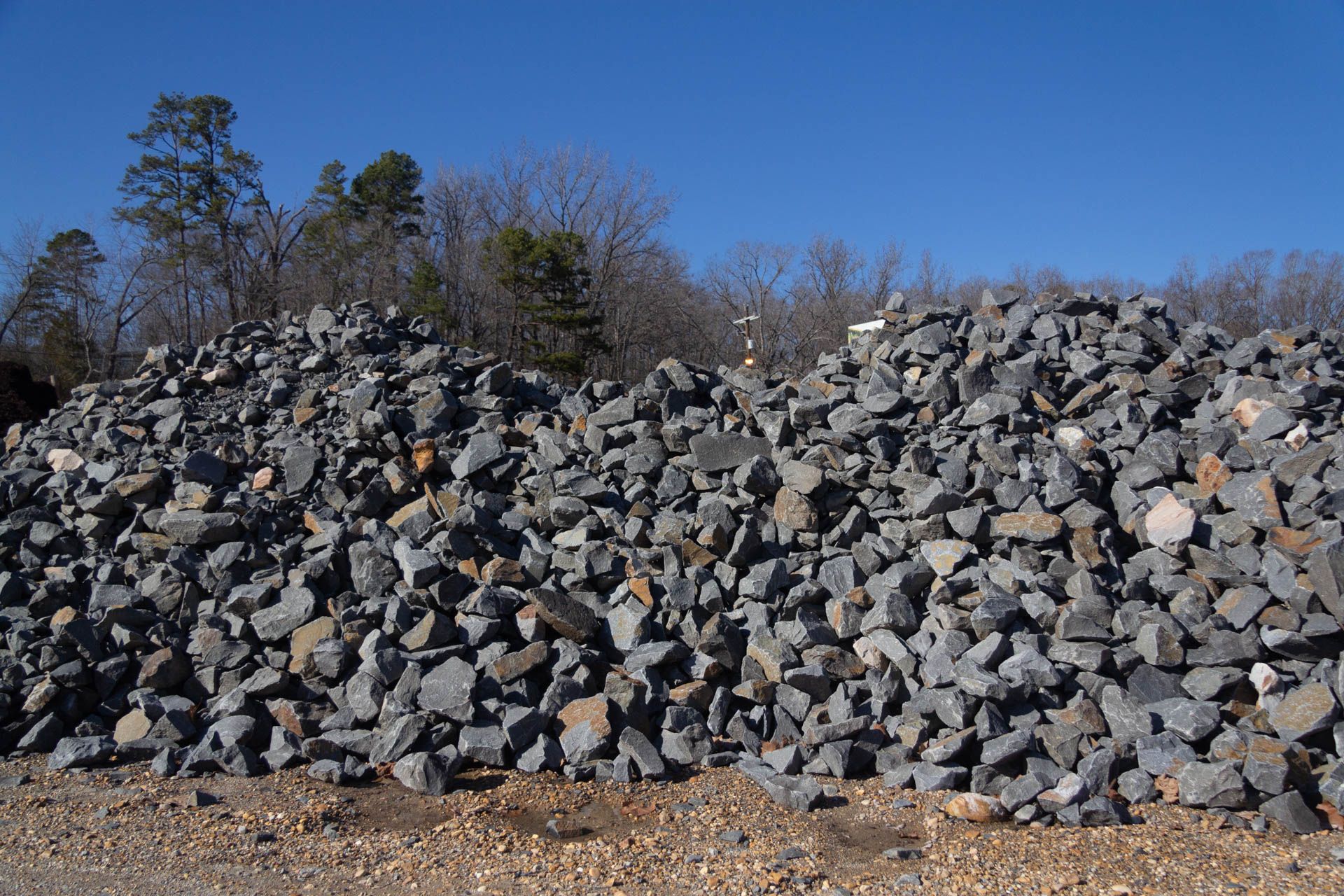A large pile of rocks is sitting on top of a dirt road.