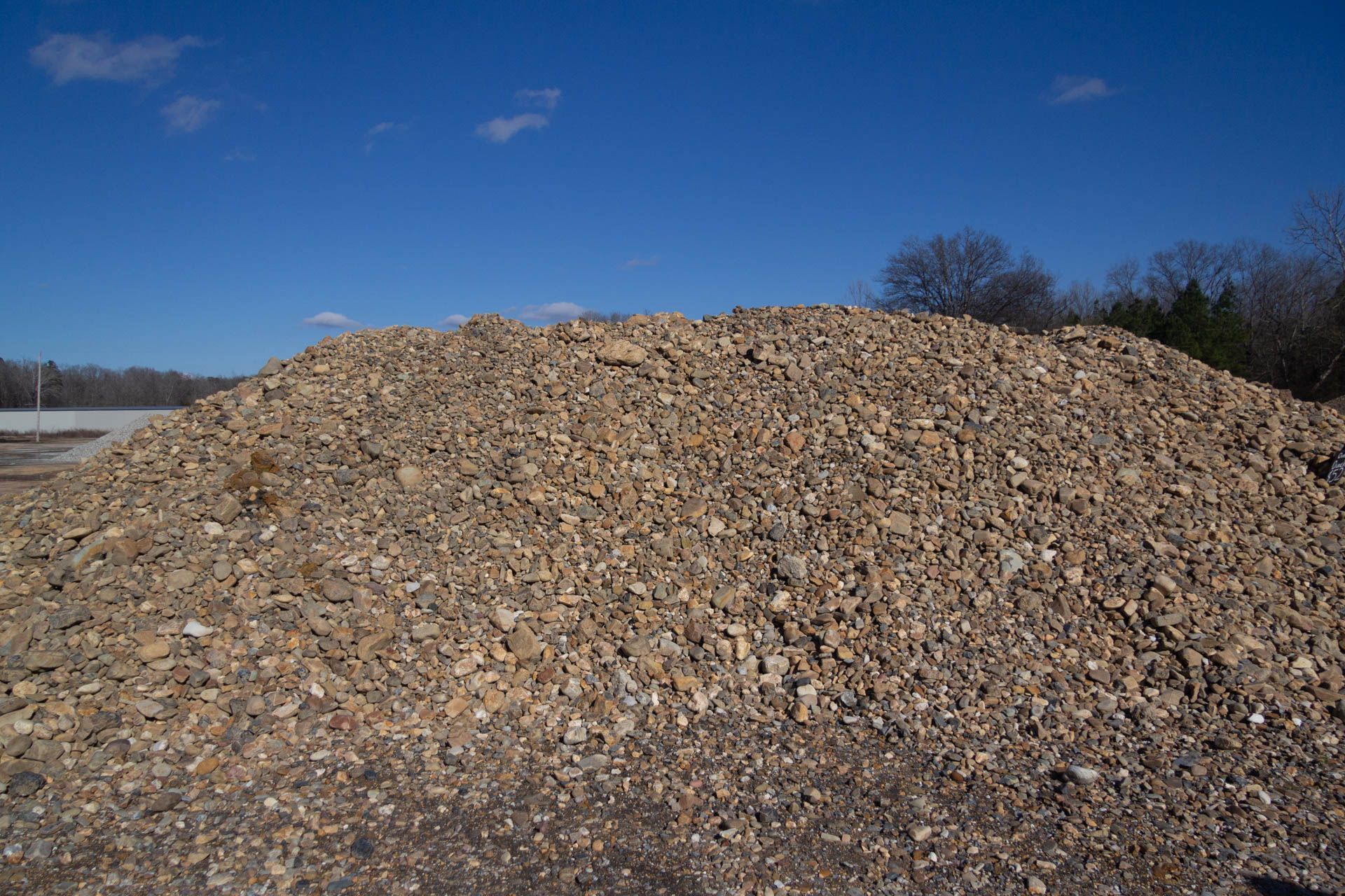 A large pile of gravel is sitting in the middle of a field.
