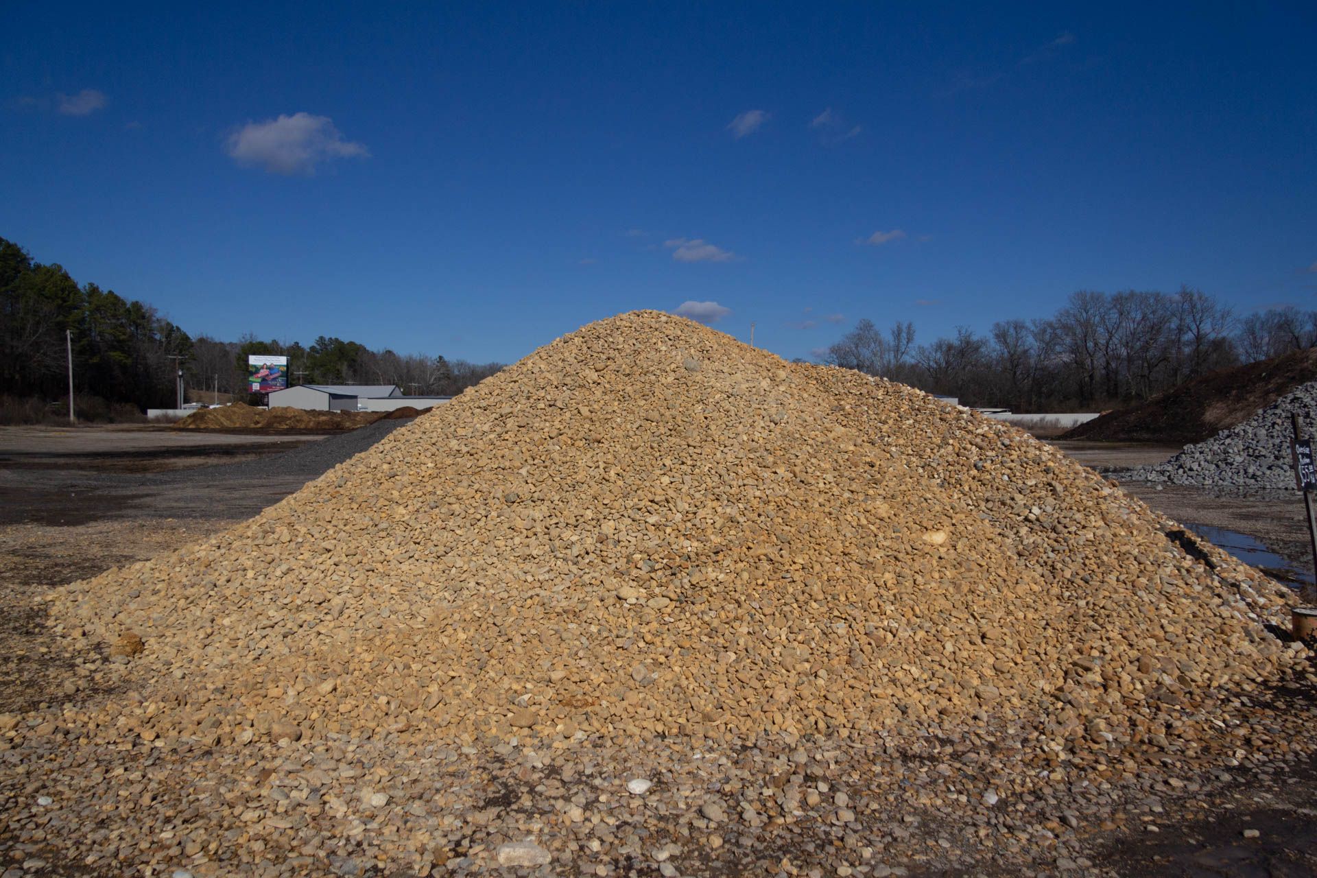 A large pile of gravel is sitting on top of a dirt field.