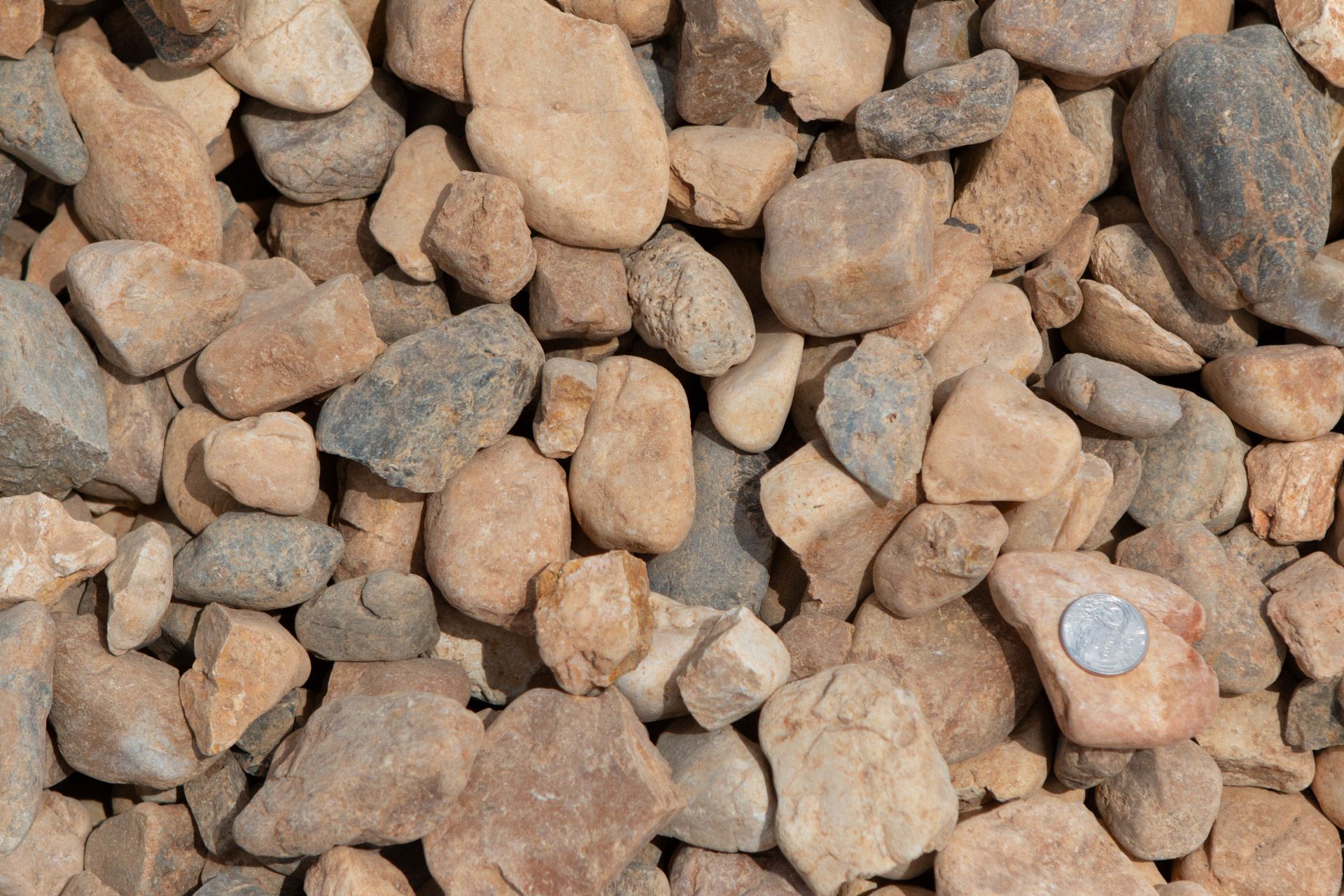 A pile of rocks with a quarter in the middle.
