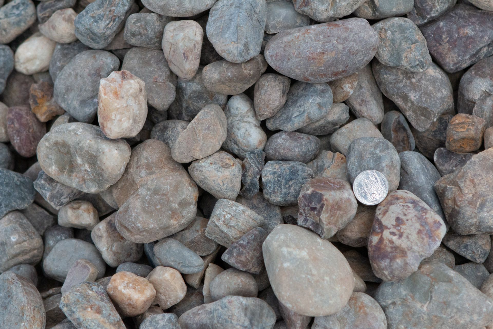 A pile of rocks with a quarter in the middle.