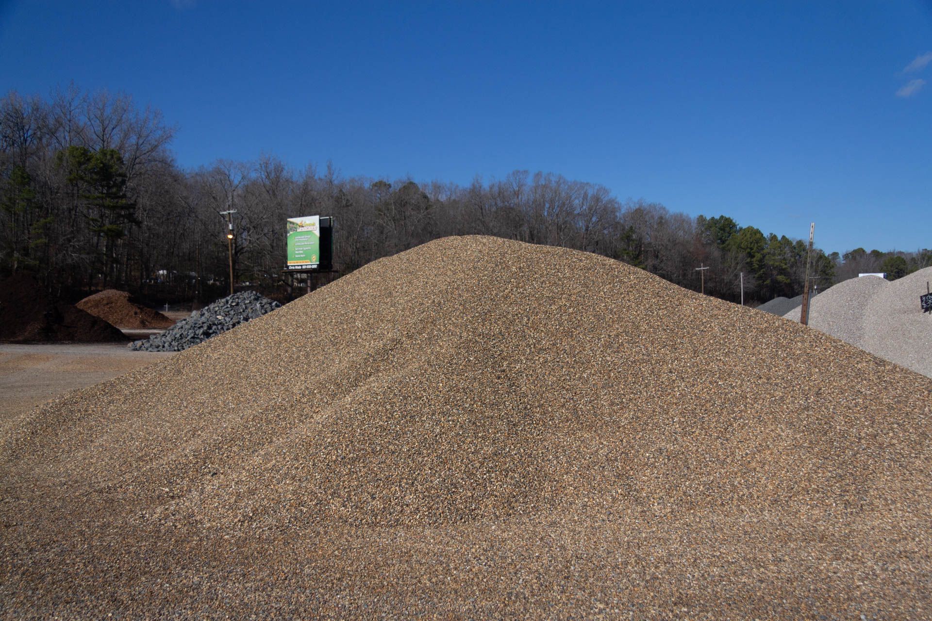 A large pile of gravel is sitting on top of a dirt field.