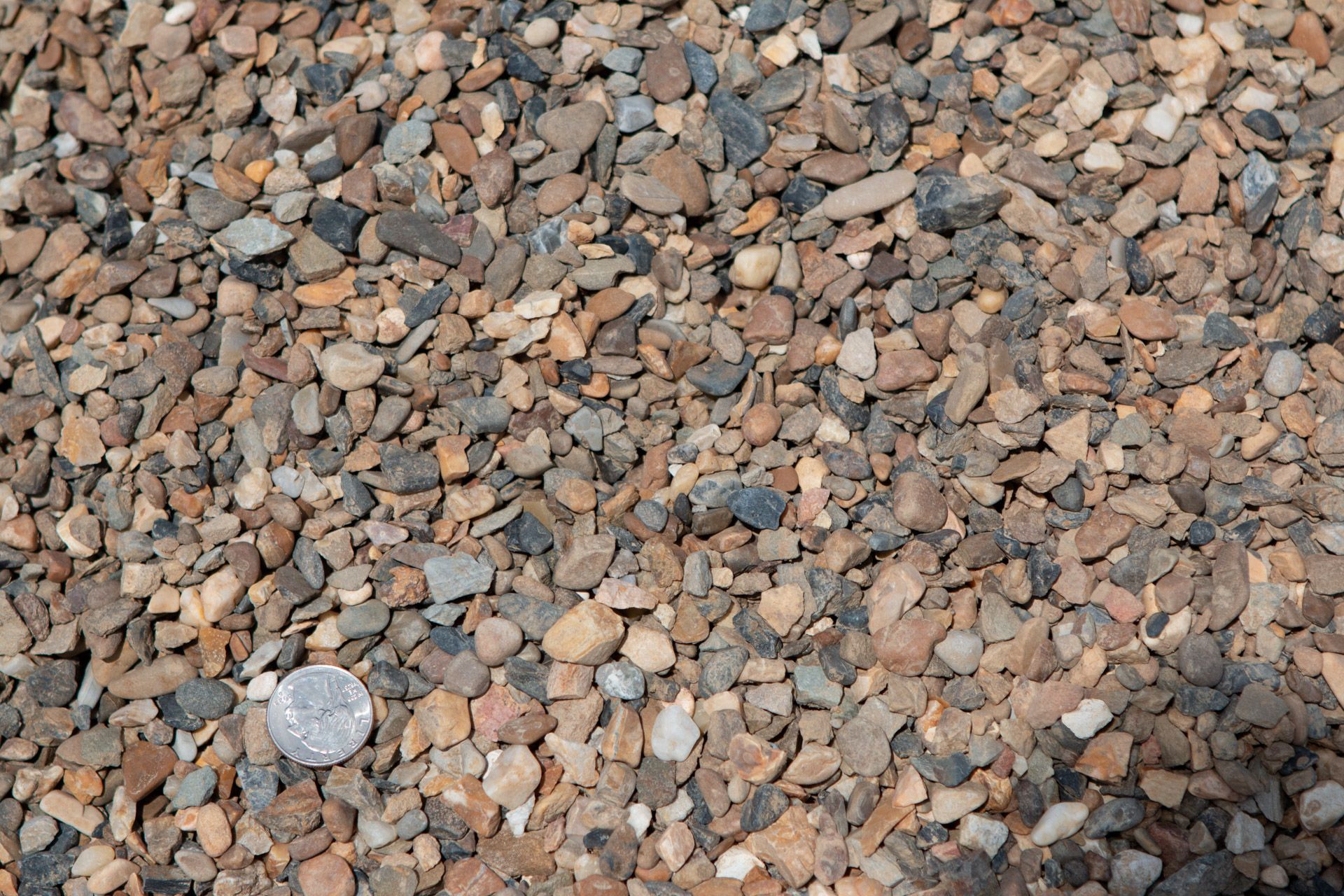 A pile of rocks with a quarter in the middle.