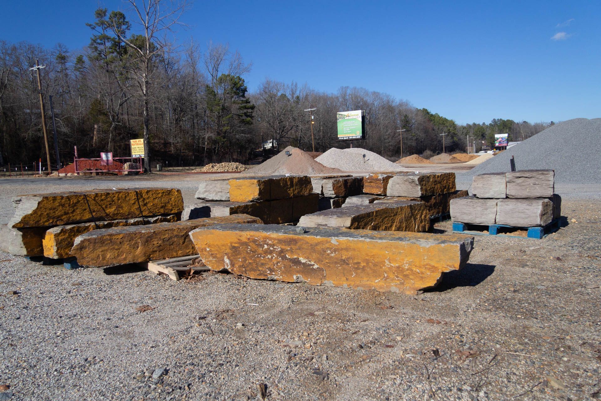 A bunch of rocks are sitting on pallets in a gravel area