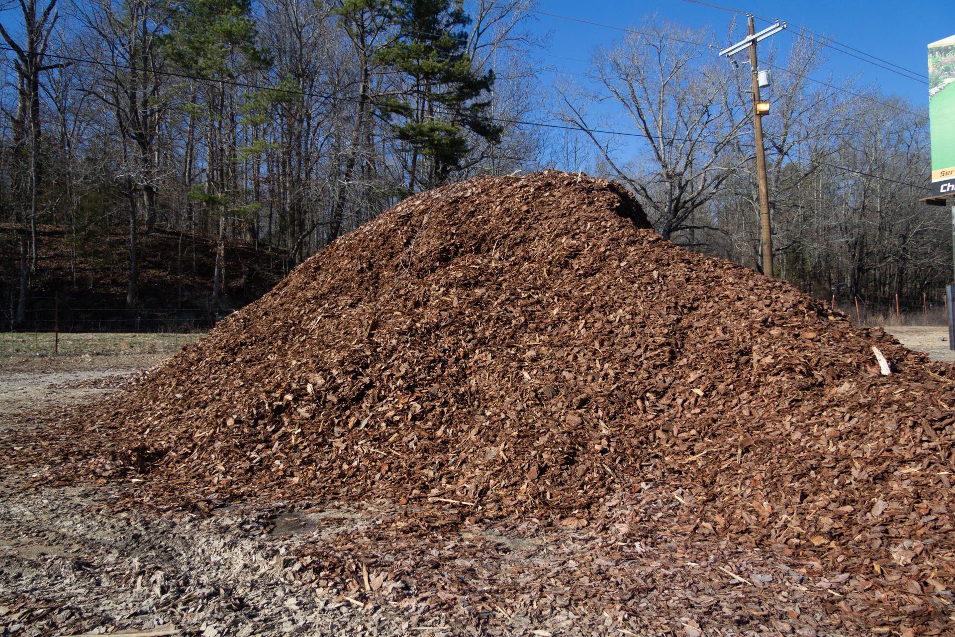 A large pile of wood chips is sitting in a field.