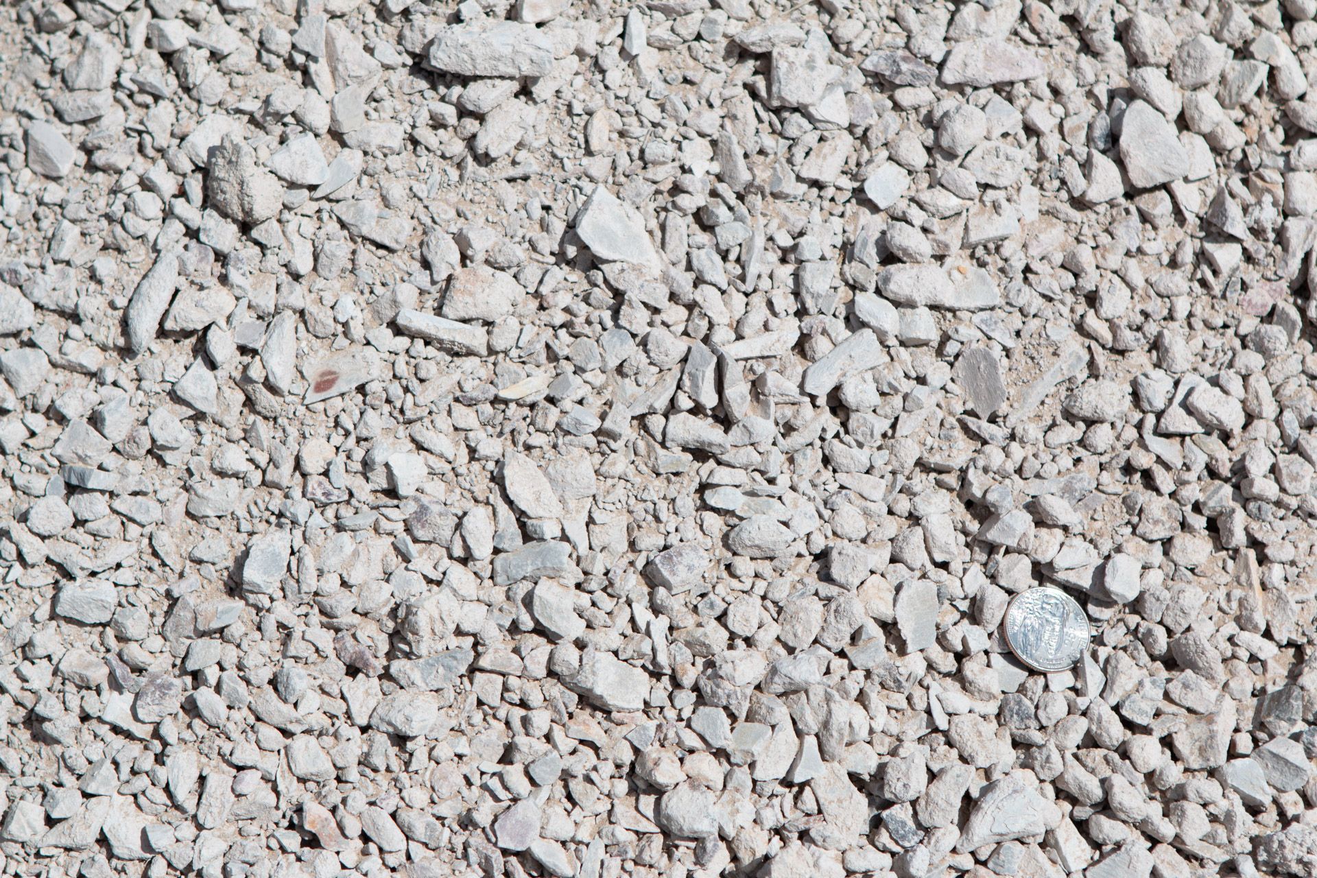 A pile of gravel with a coin in the middle.