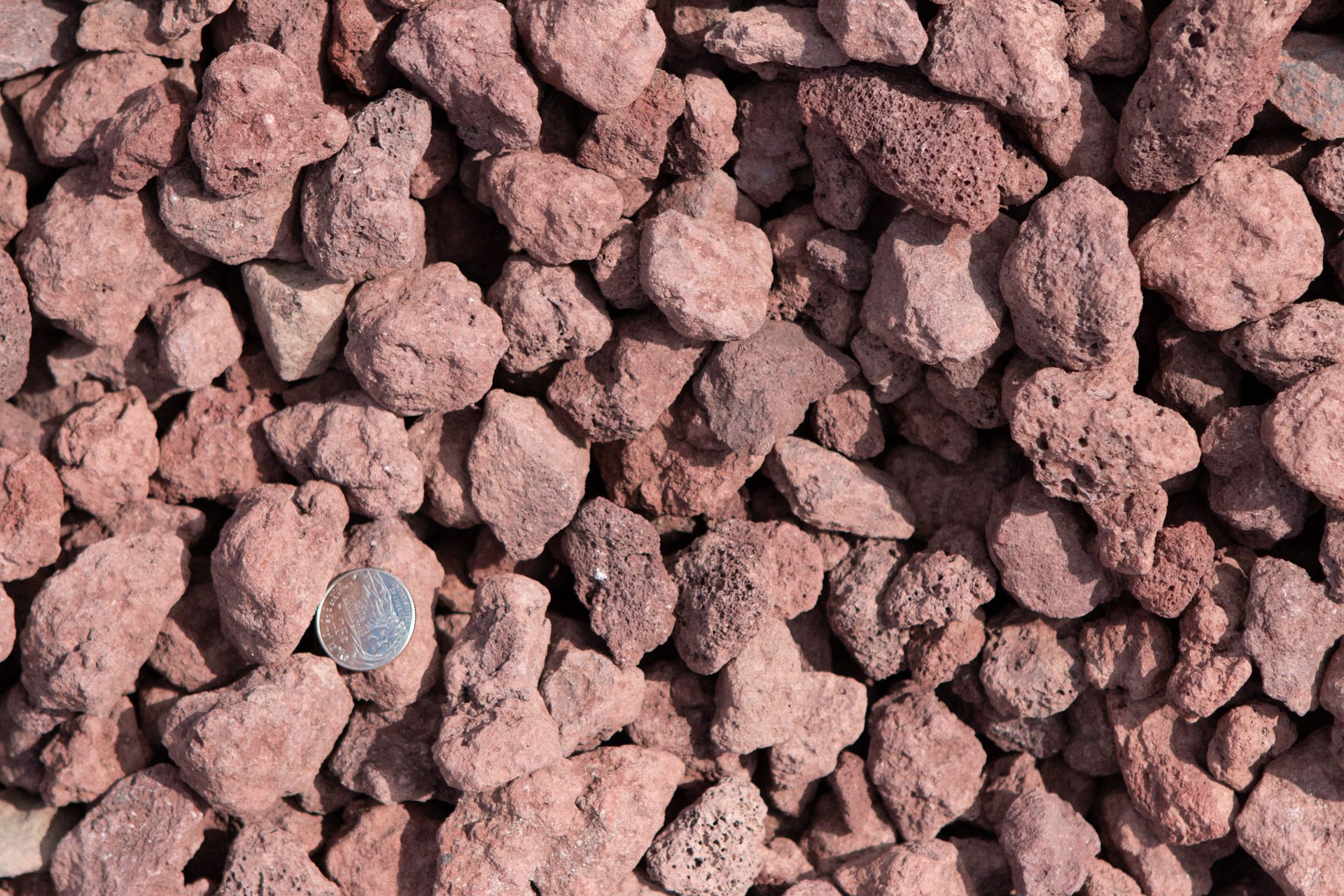 A pile of red rocks with a quarter in the middle