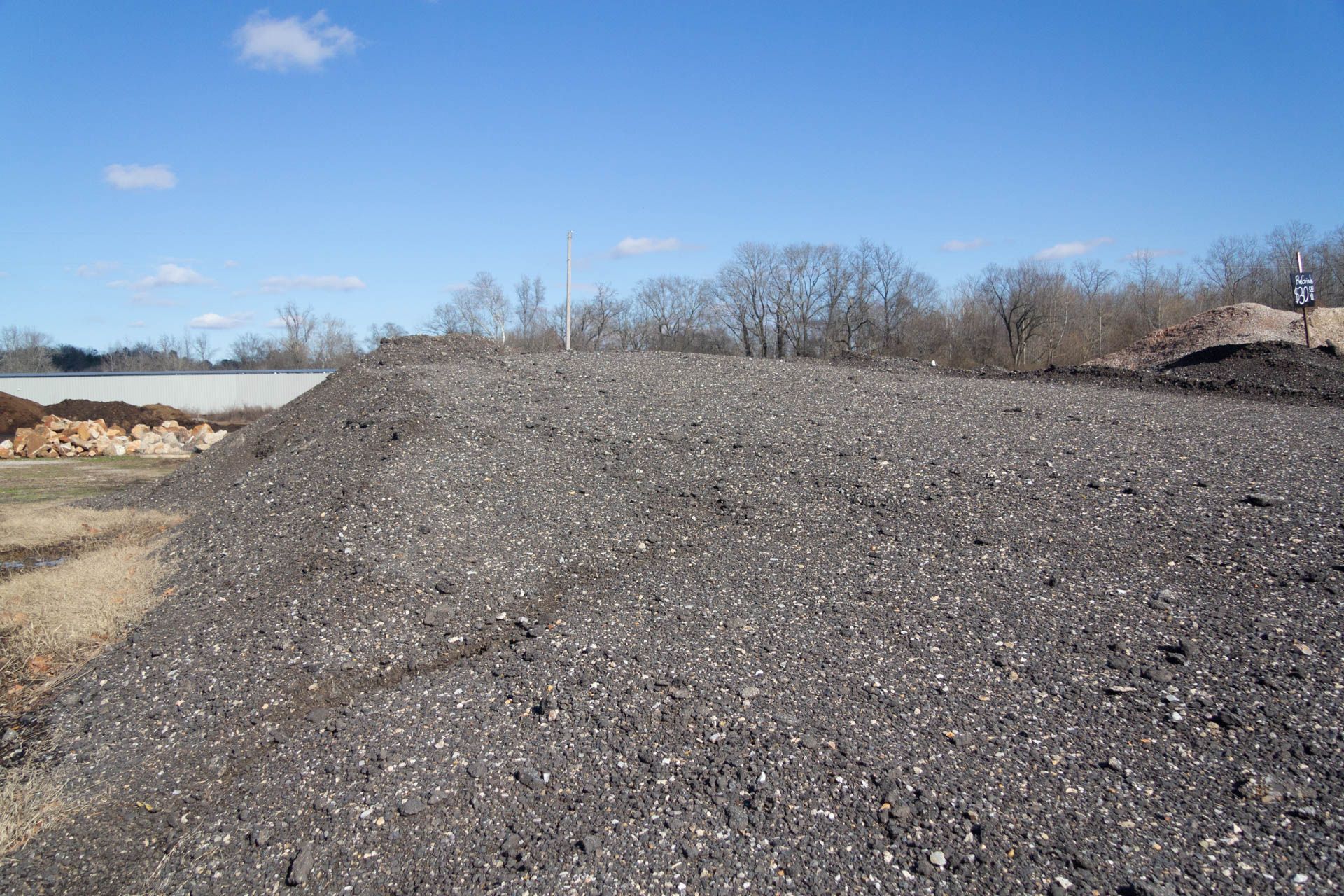 A large pile of gravel is sitting in the middle of a field.