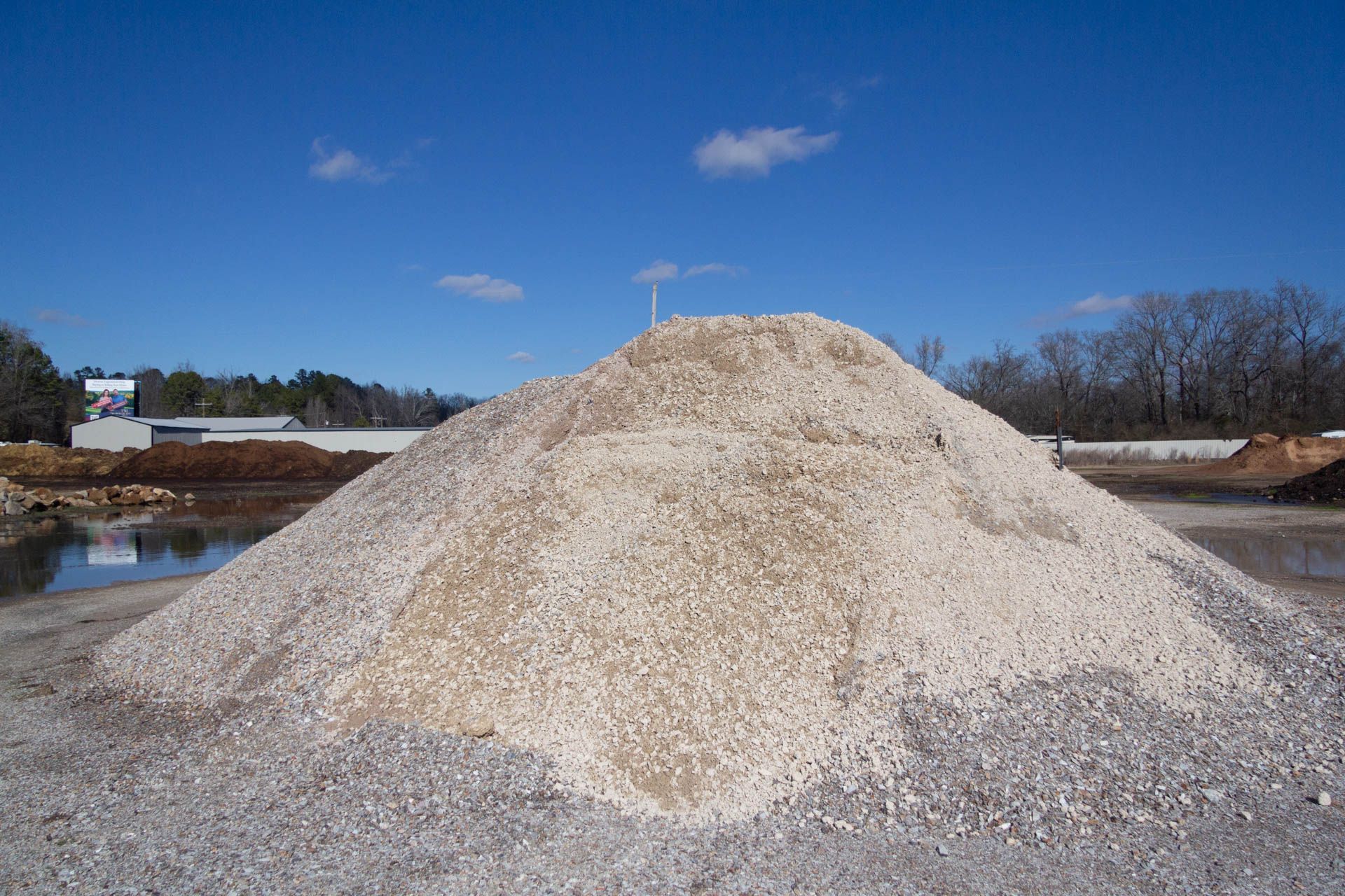 A large pile of gravel is sitting on top of a body of water.