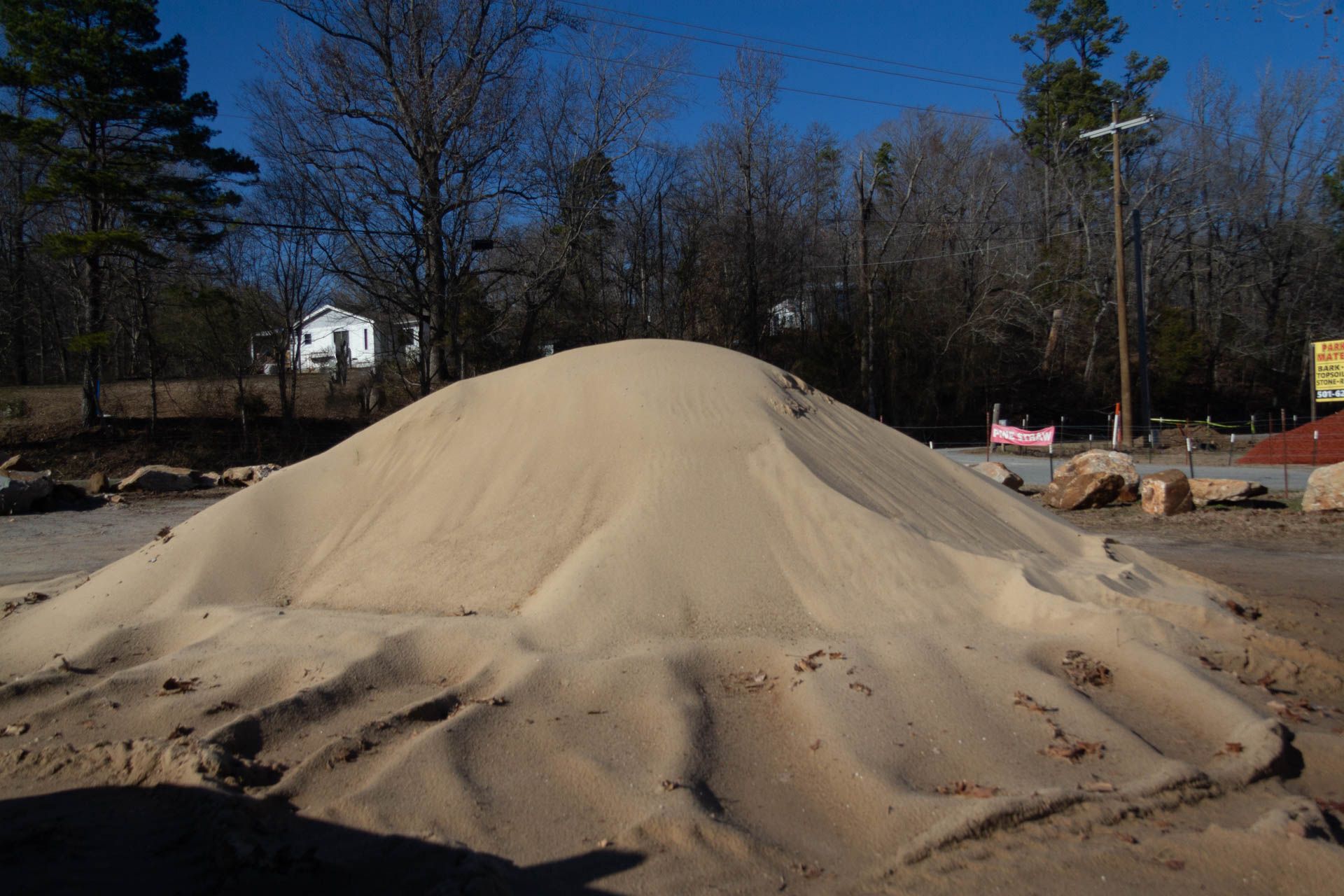 A large pile of sand is sitting in a parking lot.