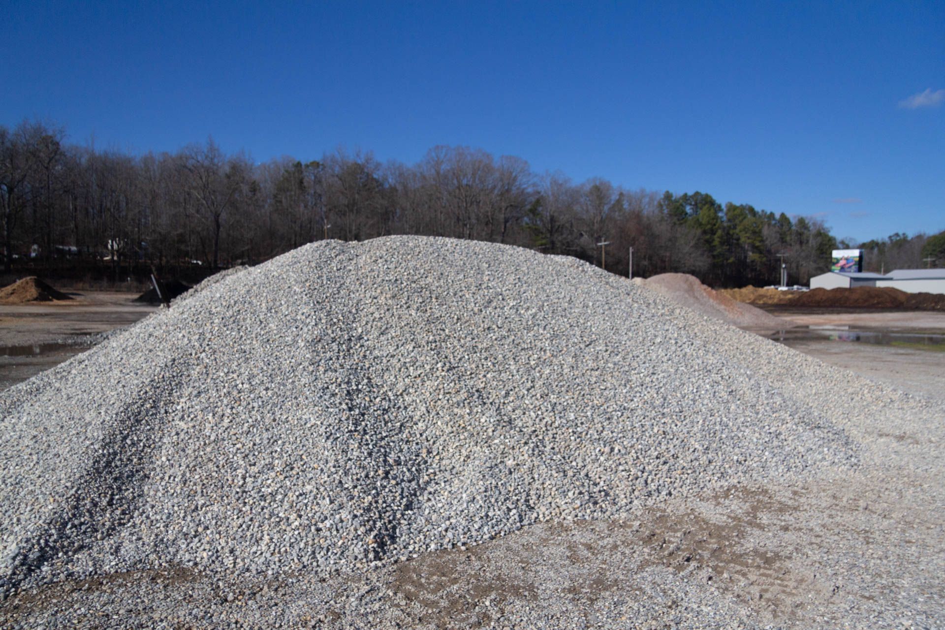 A pile of gravel is sitting in the middle of a field.
