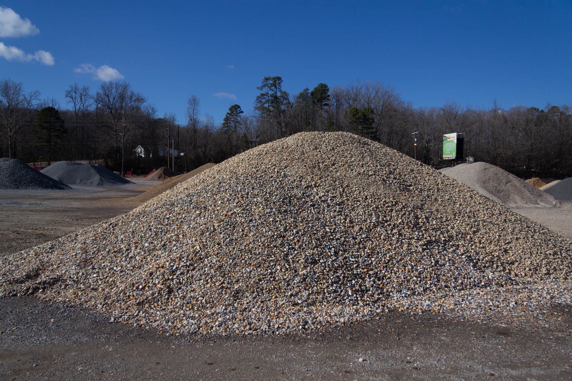 A large pile of gravel is sitting in the middle of a dirt field.