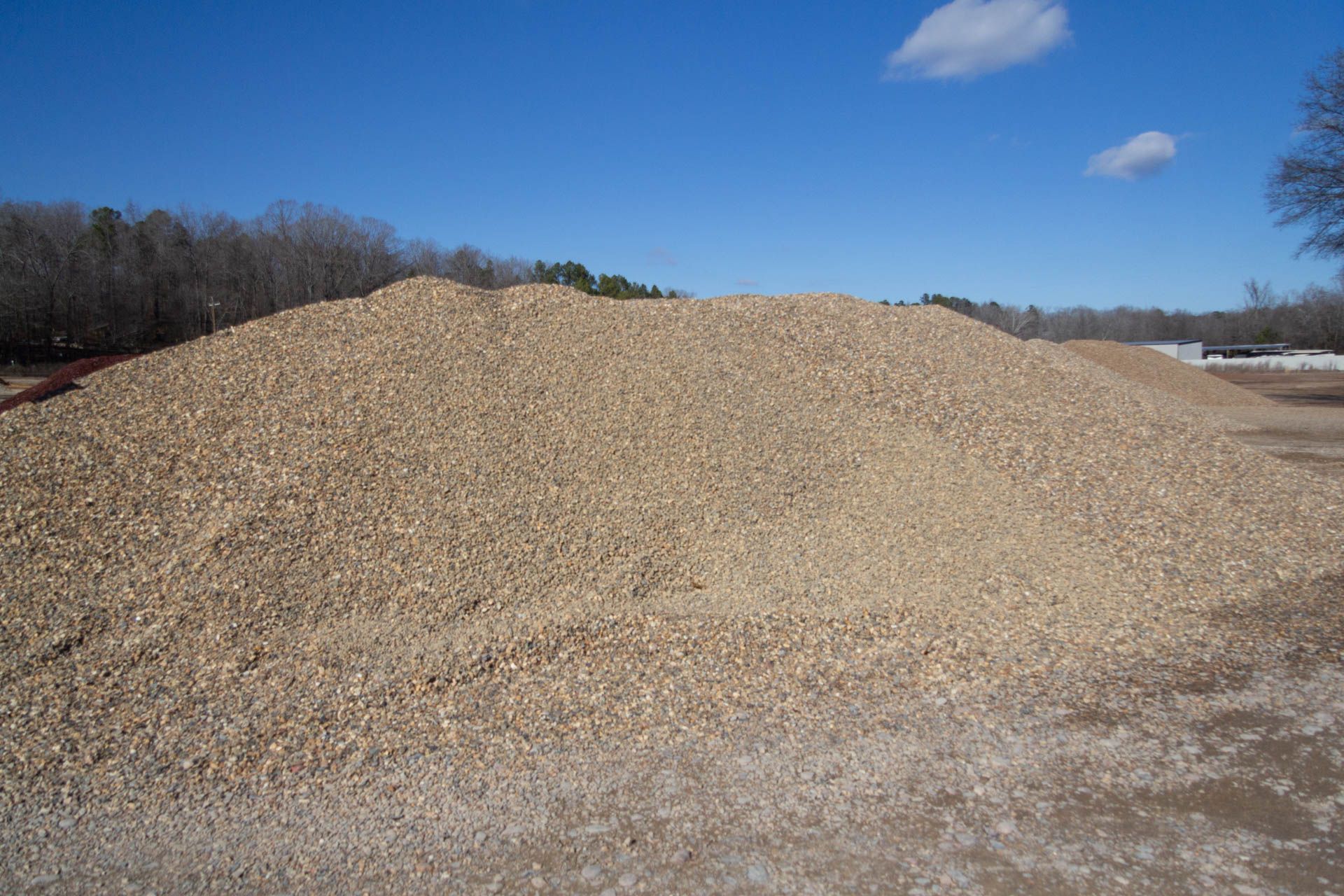 A large pile of gravel is sitting in the middle of a dirt field
