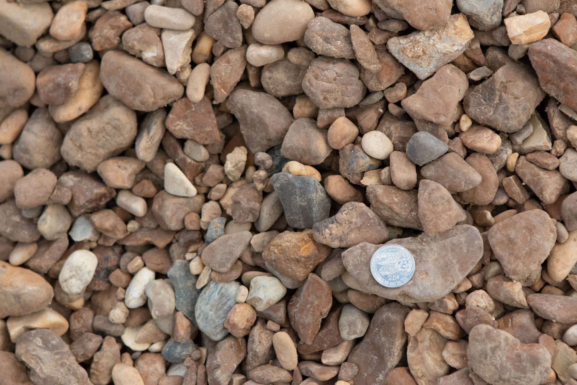 A pile of rocks with a quarter in the middle